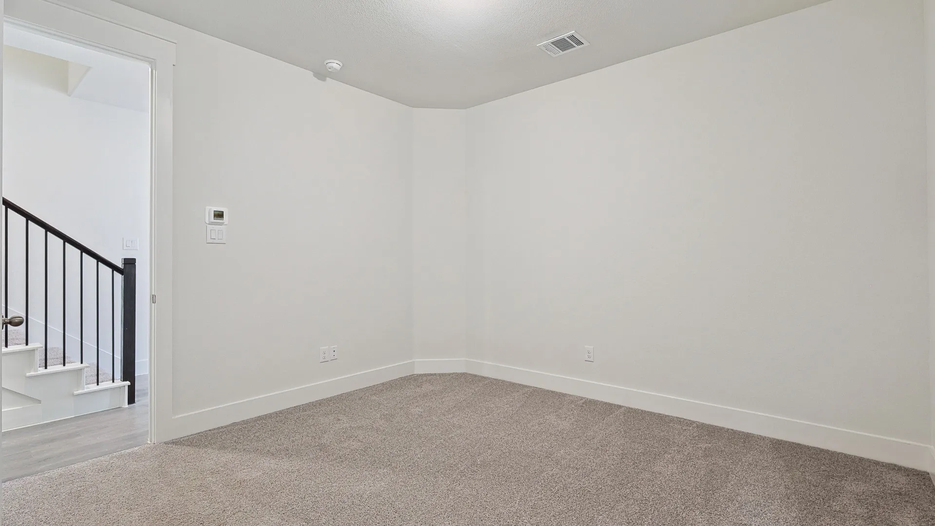 Carpeted room with white walls, white baseboards, and a white ceiling with a single ceiling light fixture