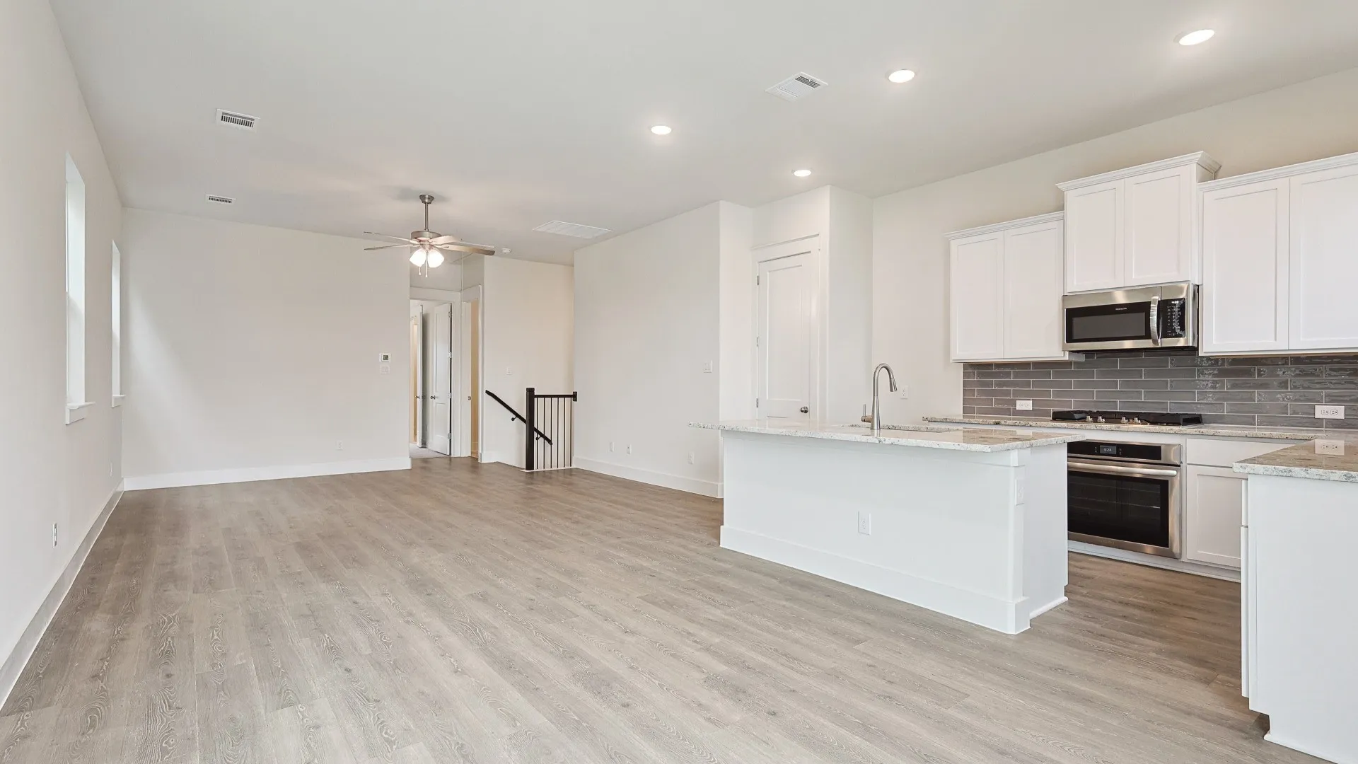 Expansive open-concept space featuring wood-finish flooring, recessed lighting, and a contemporary ceiling fan