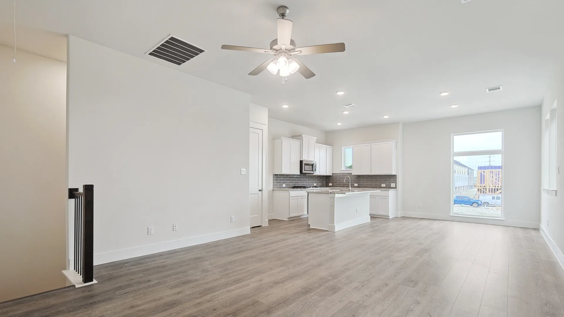 Open concept living space featuring wood-finish flooring, white walls, and a modern ceiling fan with integrated lighting