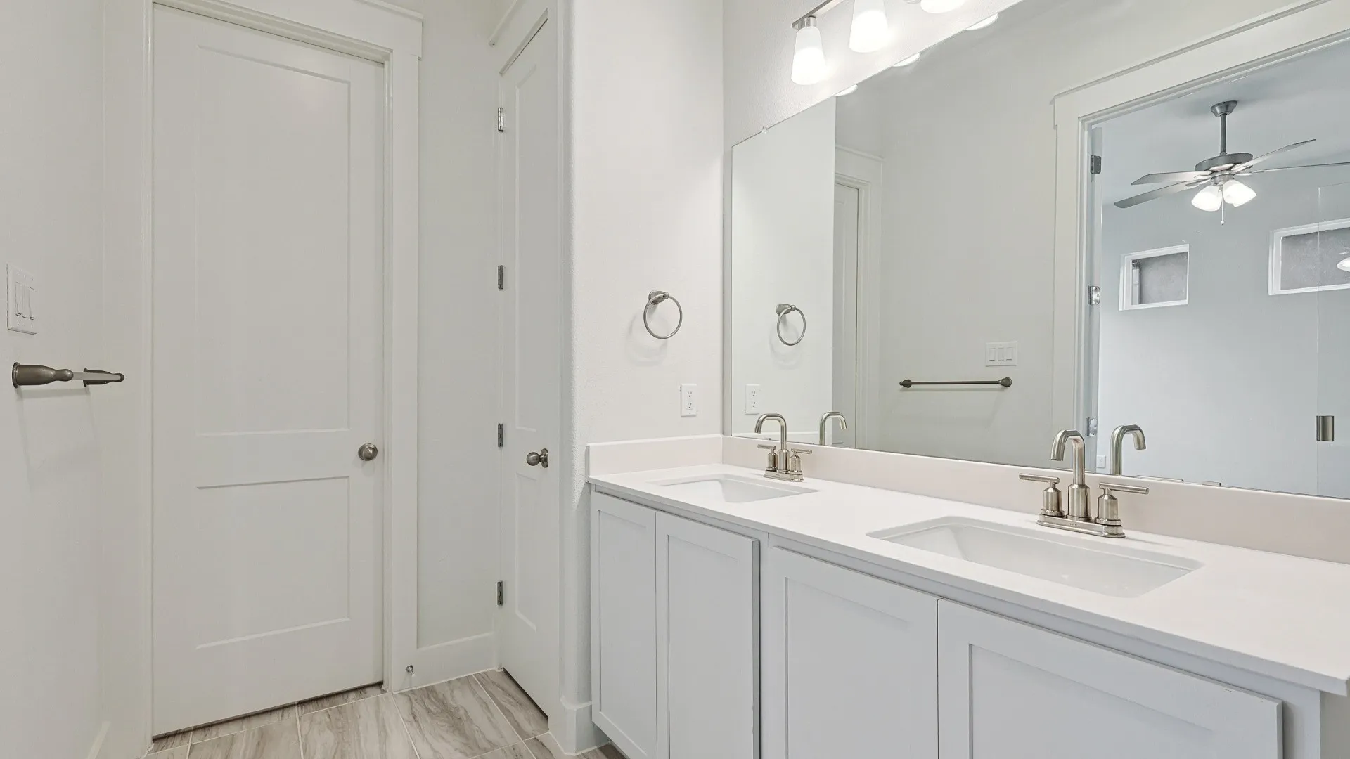 Double vanity with white cabinetry, light-toned countertops, and brushed nickel fixtures