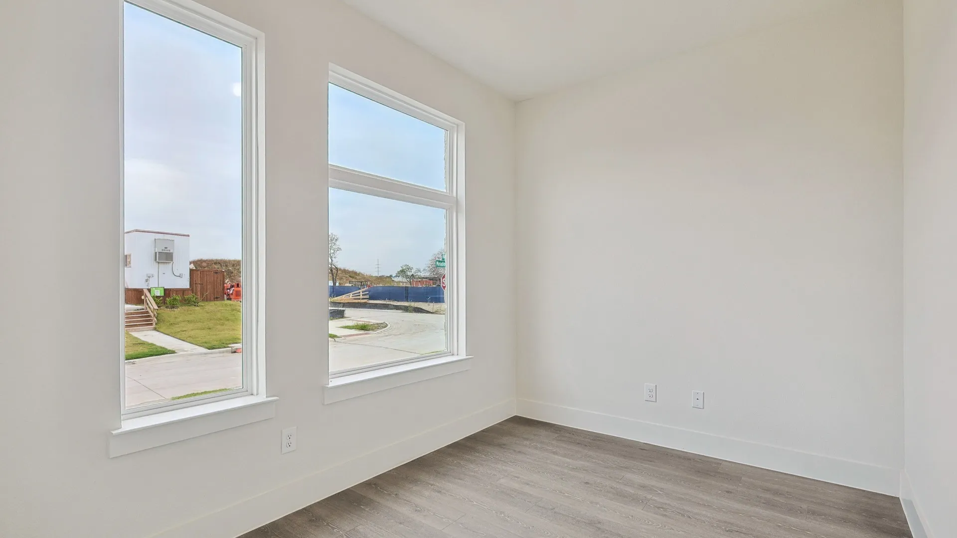 Bright interior space featuring multiple windows, wood-finish flooring, white baseboards, and neutral wall finishes