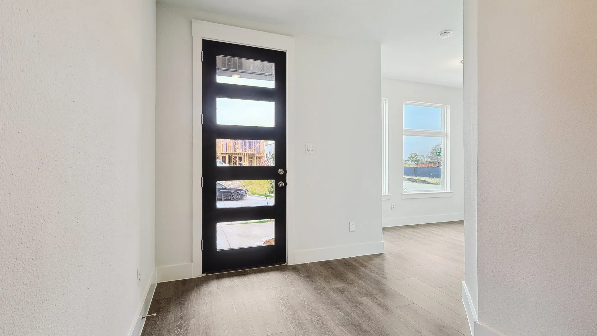 Modern panel-lite entry door featuring a matte black finish and brushed nickel hardware