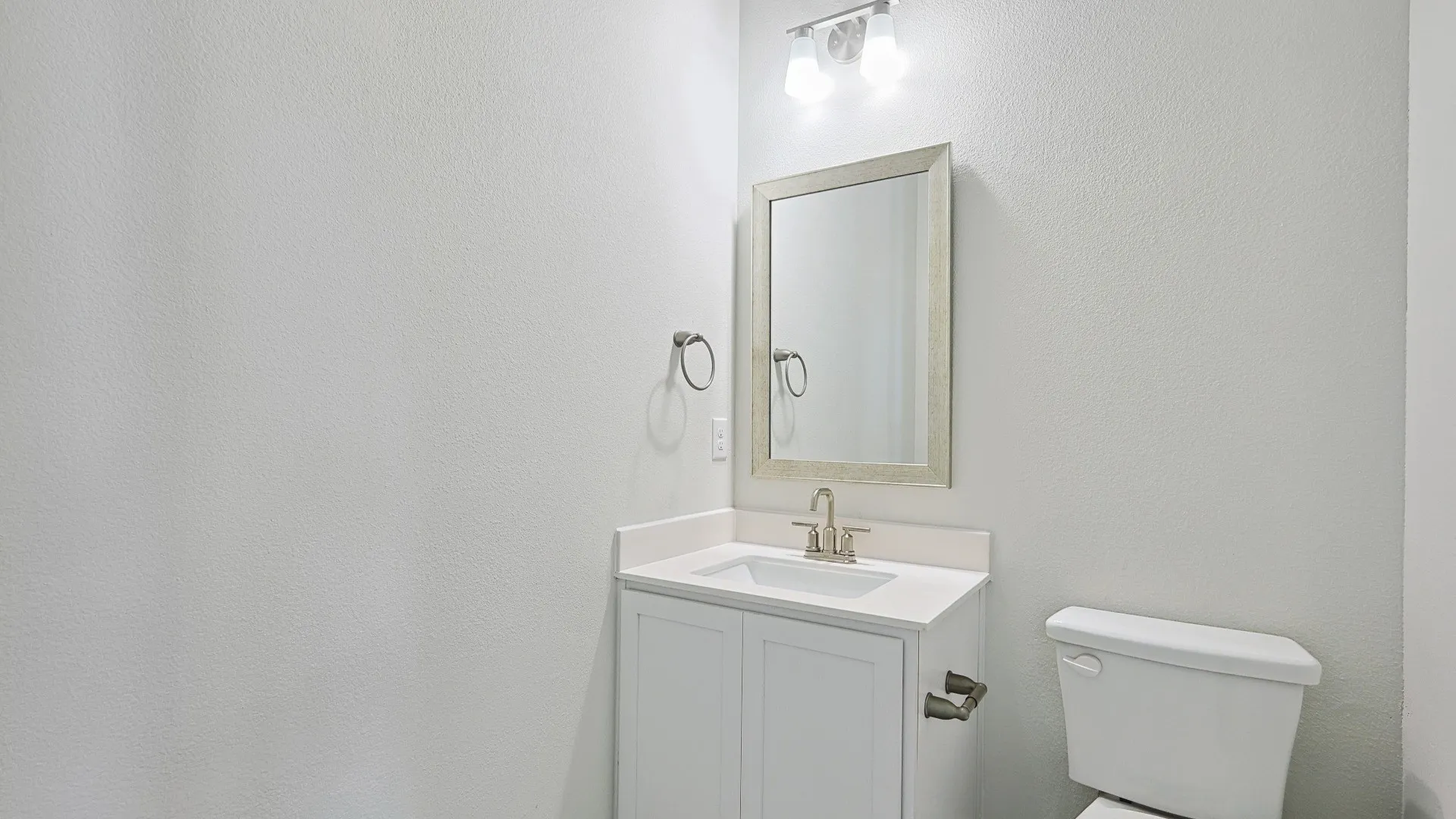 White vanity with a built-in sink, brushed nickel faucet, and a framed mirror