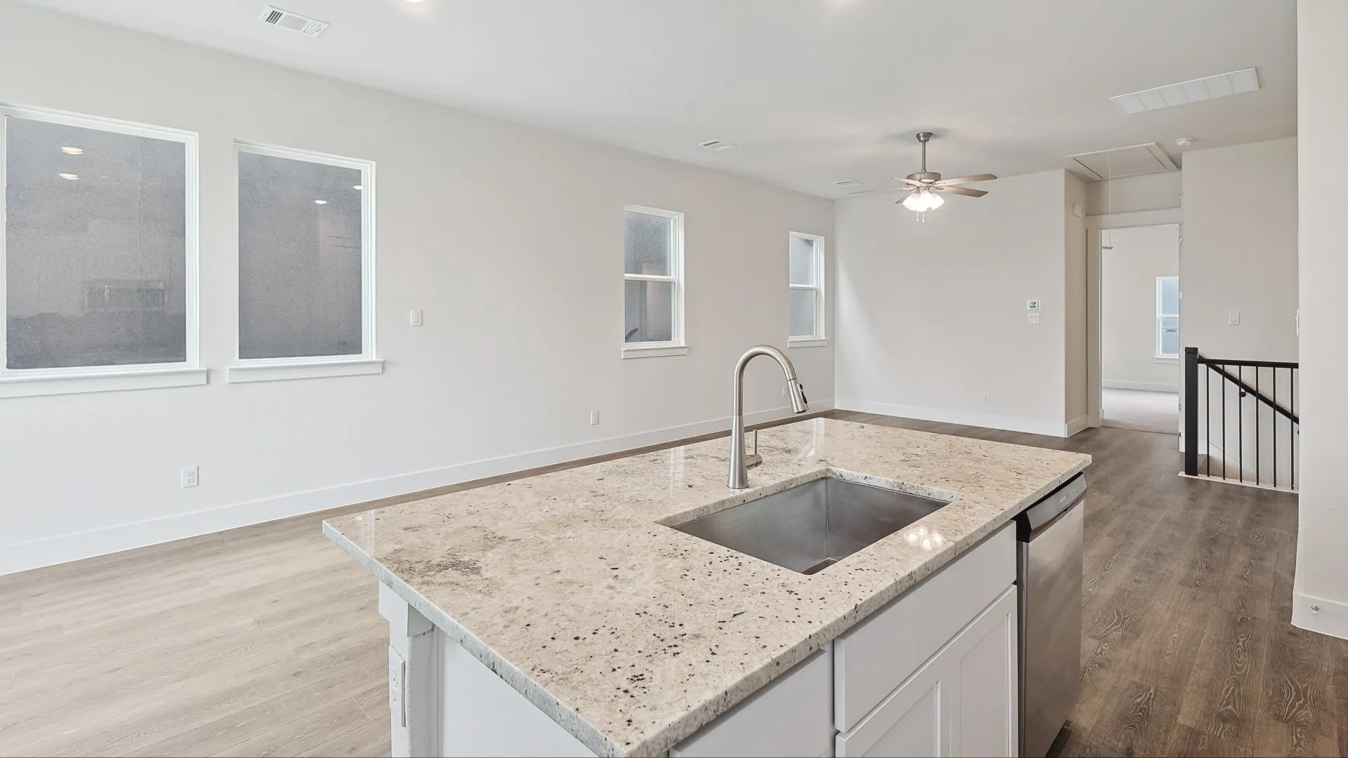 Kitchen island featuring a stainless steel sink, gooseneck faucet, and light-toned granite countertop