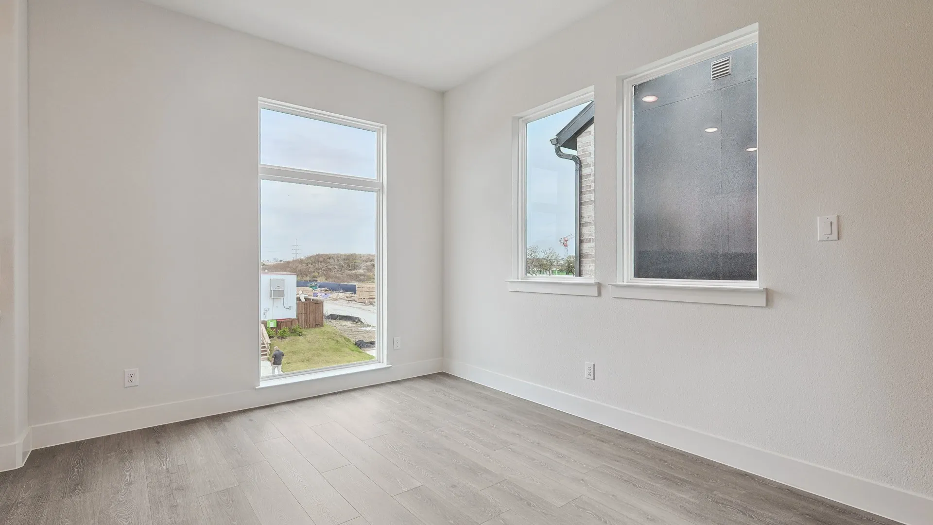 Room featuring light gray wood-finish flooring, white baseboards, and white walls