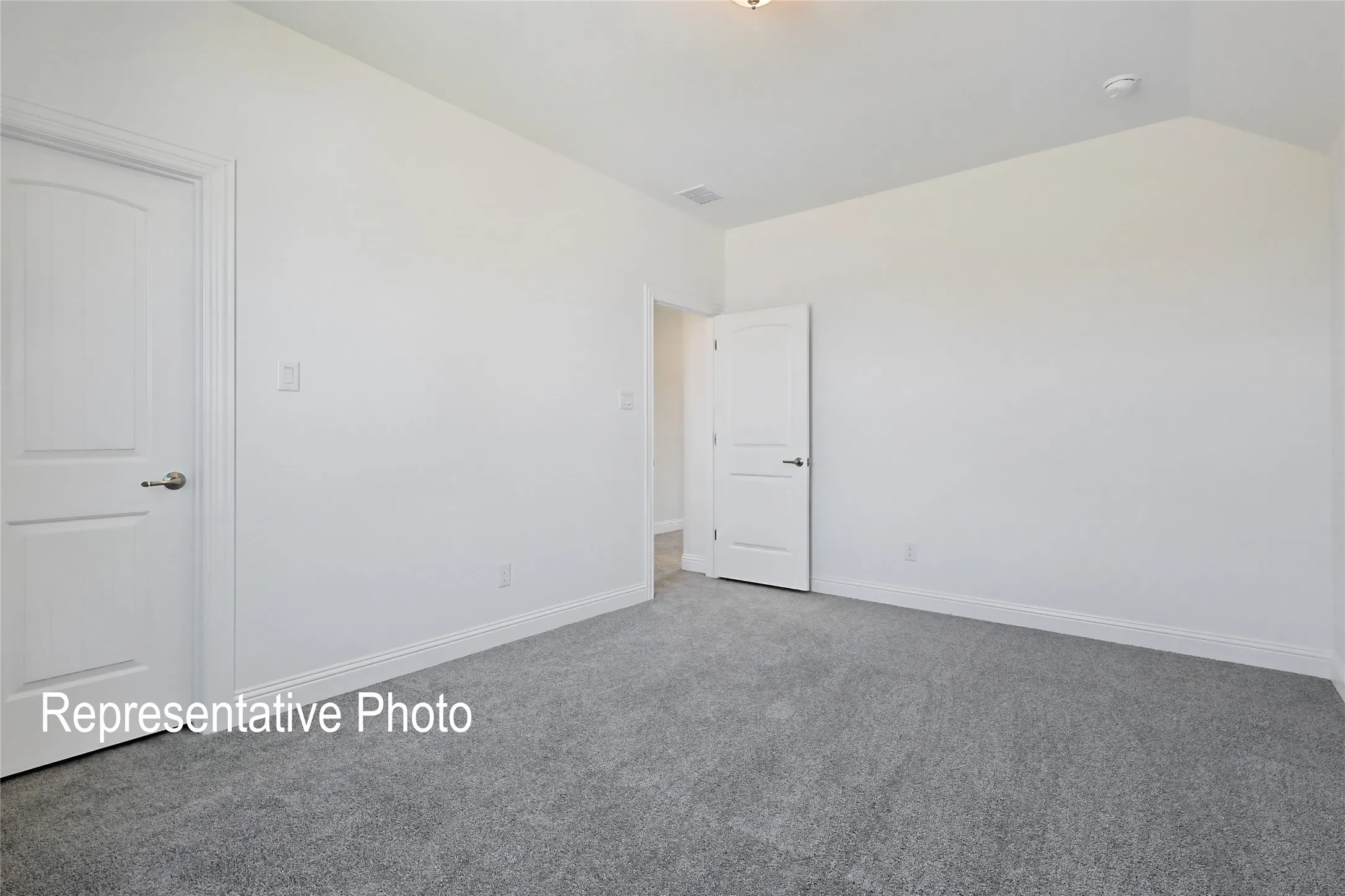 Spacious room featuring light gray carpeting and bright white walls