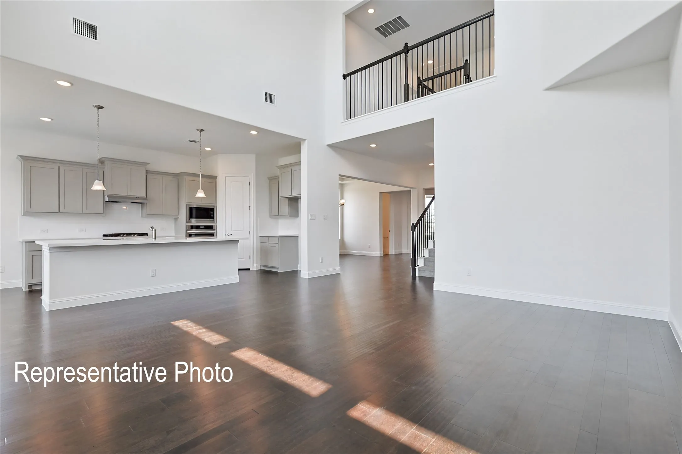 Open-concept living area with wood-finish flooring and a two-story ceiling