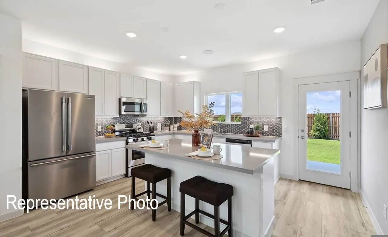 Bright kitchen featuring an expansive island with a light countertop, stainless steel appliances, white cabinetry, and wood-finish flooring