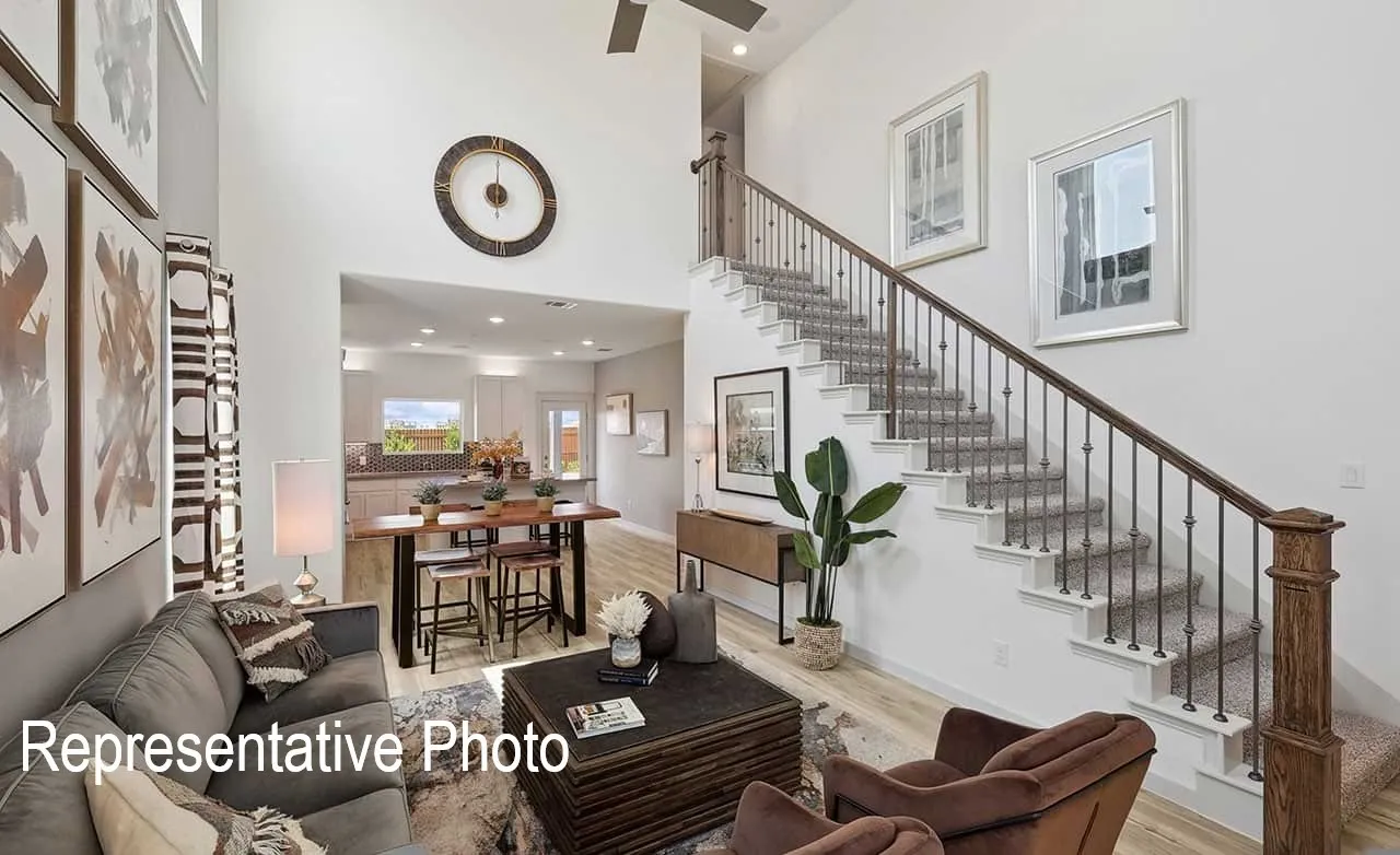 Two-story living area featuring a prominent staircase with dark wood handrails and metal balusters, high ceilings, light wood-finish flooring, and recessed lighting