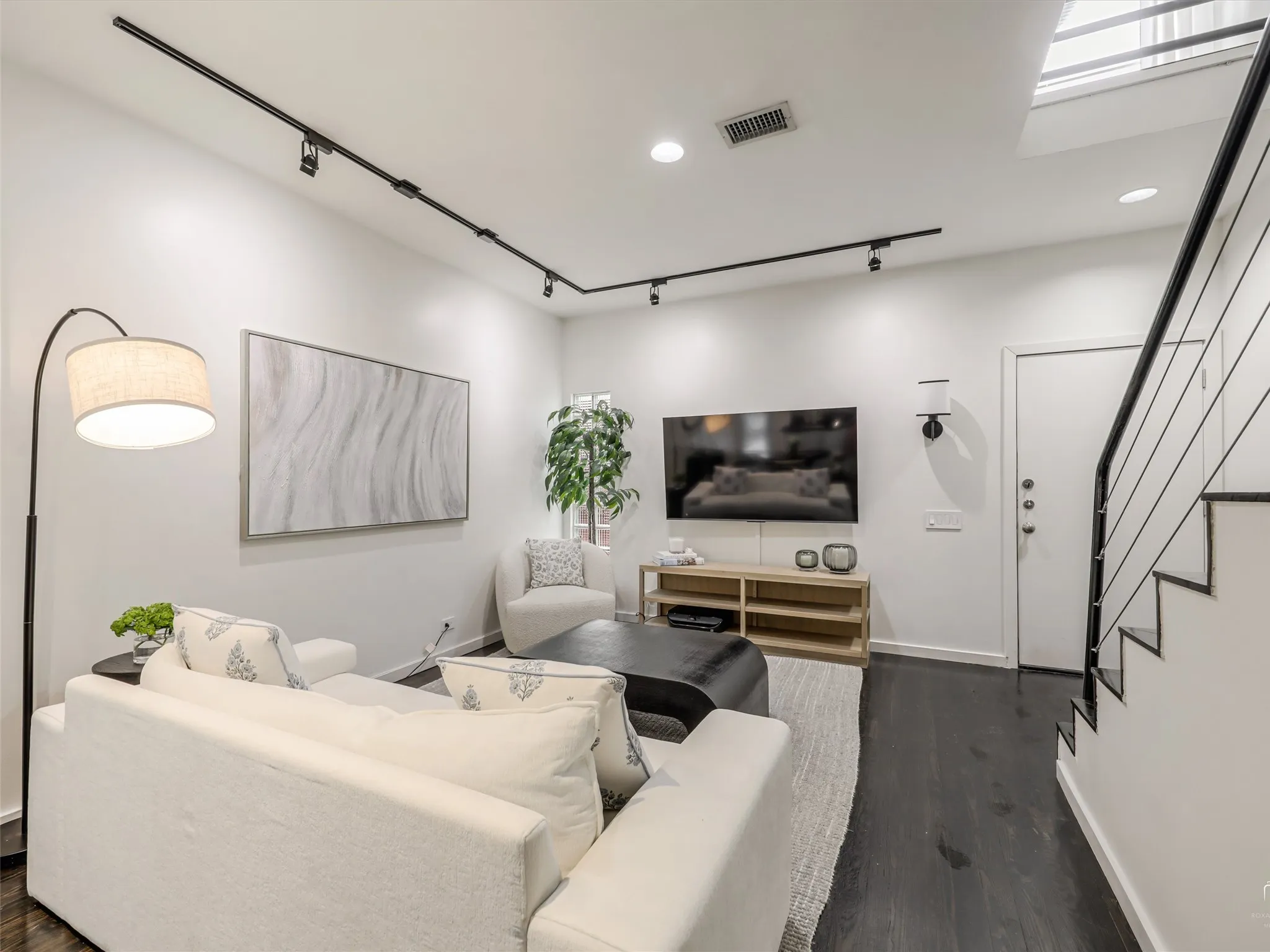 Living space featuring dark wood-finish flooring, white walls, and a modern track lighting system
