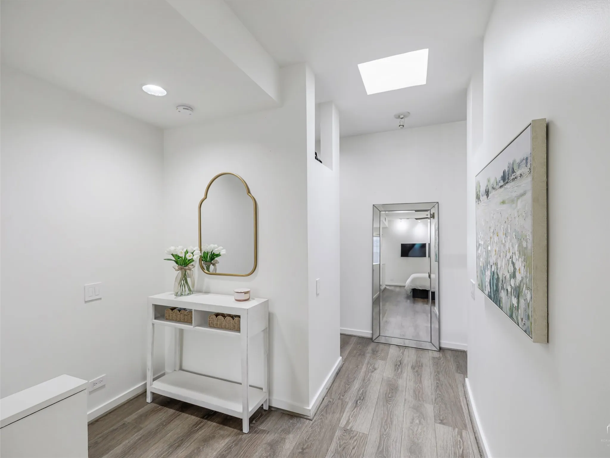 Hallway featuring wood-finish flooring, recessed lighting, and a prominent skylight