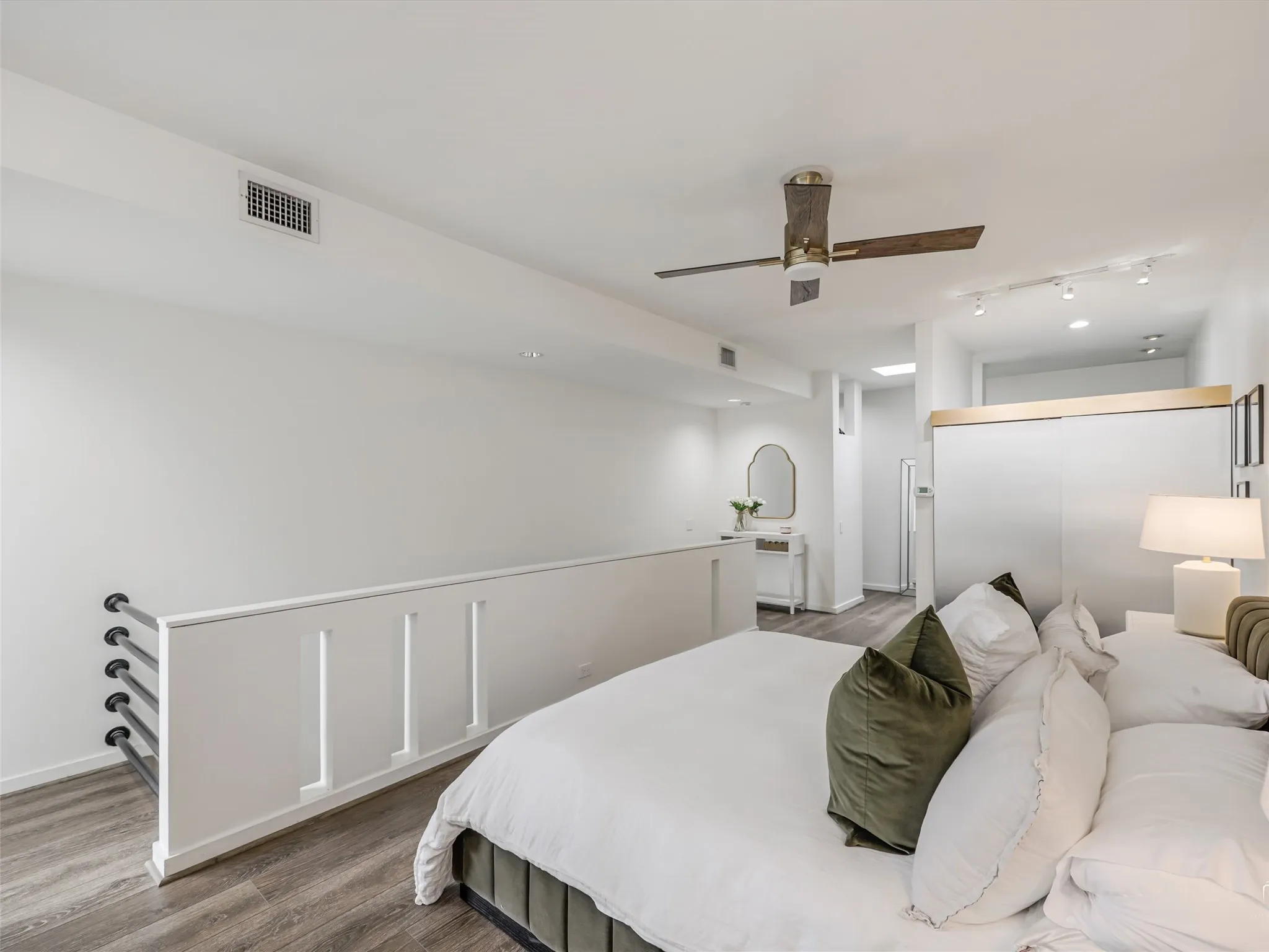 Loft-style bedroom featuring wood-finish flooring, a contemporary ceiling fan, and recessed lighting