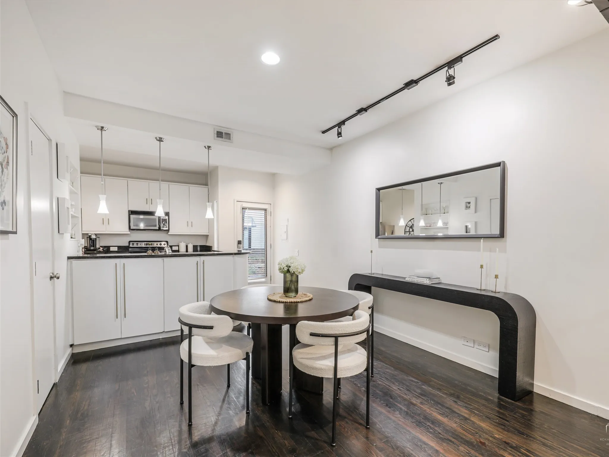 Open-concept living area featuring dark wood-finish flooring, white walls, and a modern kitchen