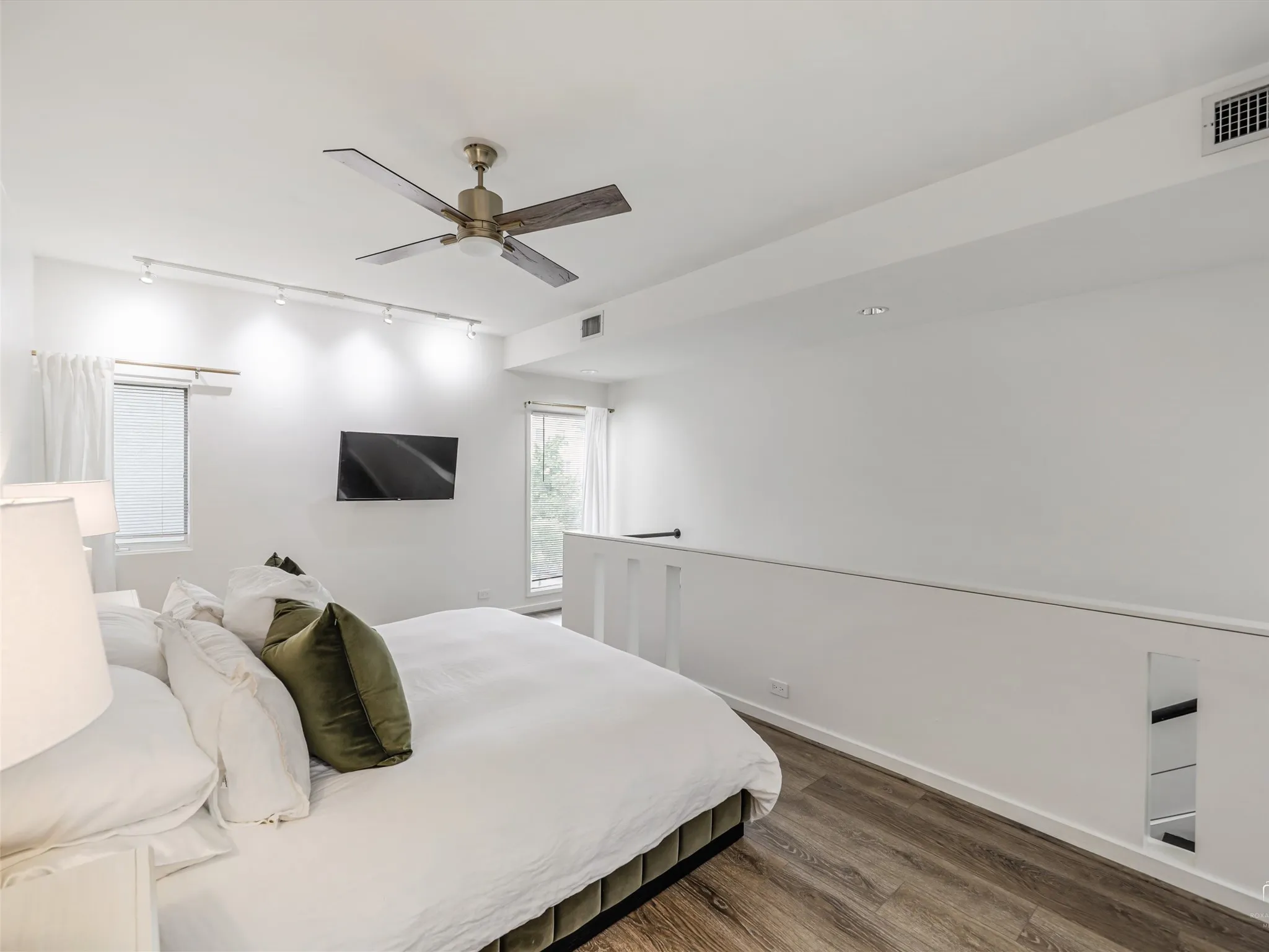 Open-concept bedroom with wood-finish flooring, a ceiling fan, and track​​‌​​​​‌​​‌‌​‌‌​​​‌‌​‌​‌​‌​​​‌​​ lighting