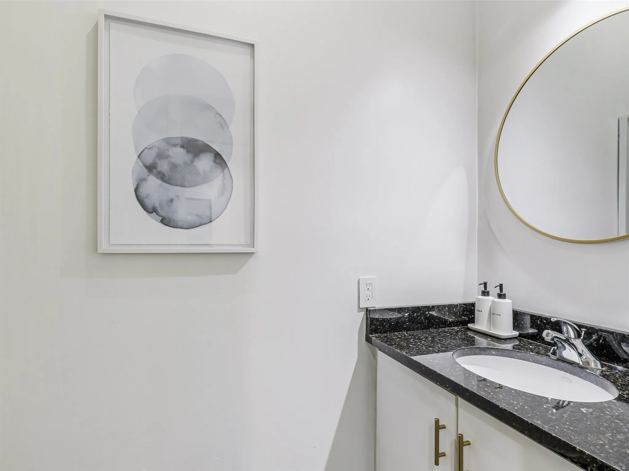 Powder Bath Vanity with a dark speckled countertop, undermount sink, and brass-tone hardware