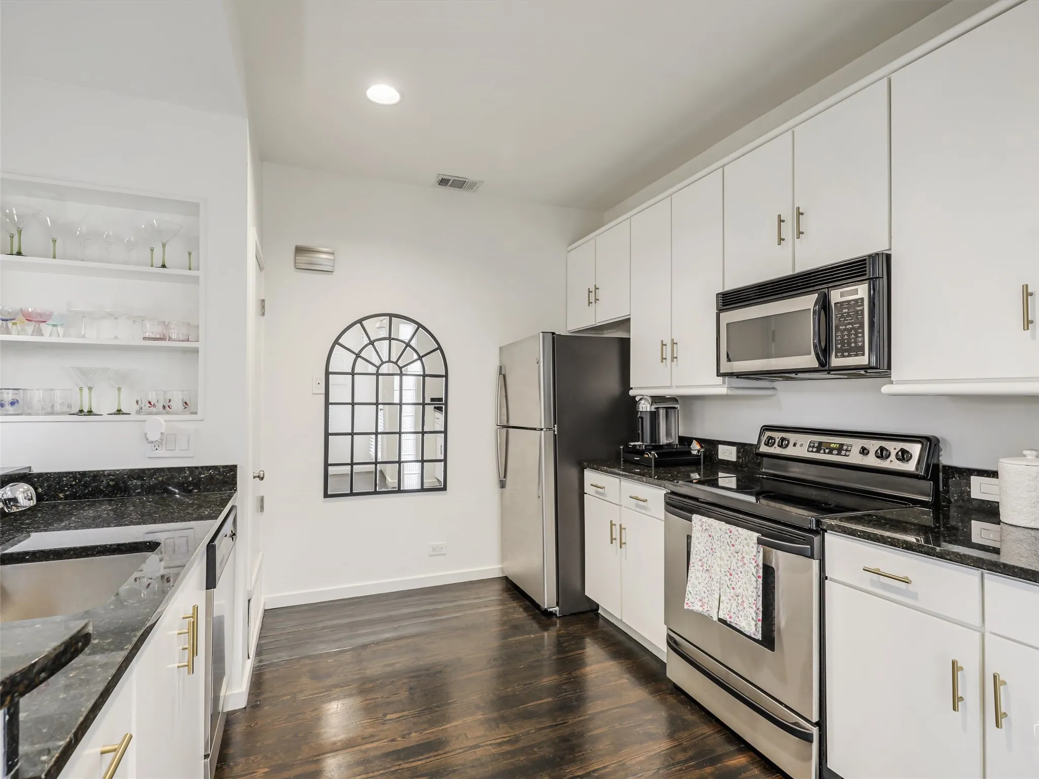 Kitchen featuring white cabinetry, dark stone countertops, stainless steel appliances, and dark wood-finish flooring