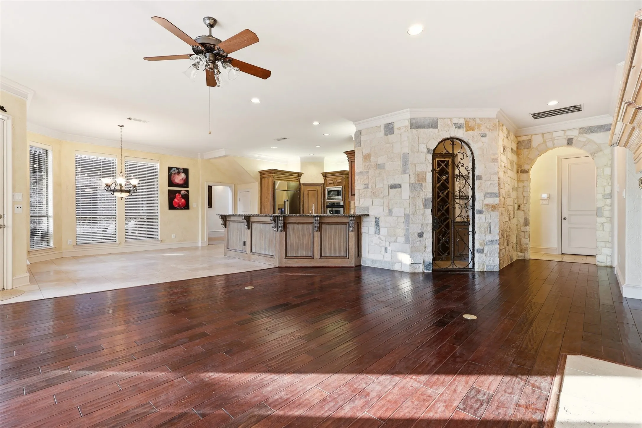 Dark wood-finish flooring, stone accent walls, arched doorway, and built-in wine storage