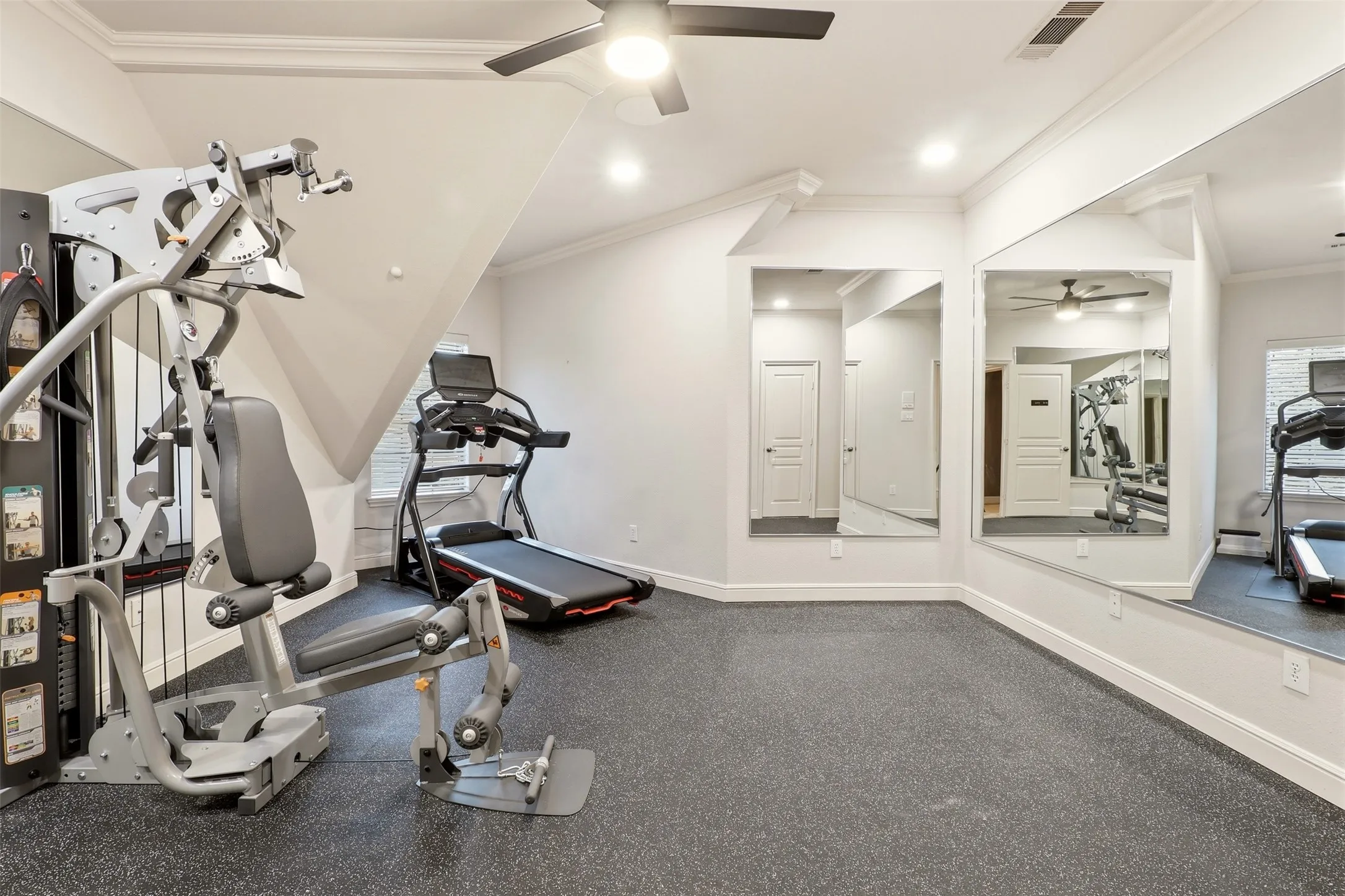Dedicated exercise space featuring durable rubber flooring, wall-mounted mirrors, and an angled ceiling