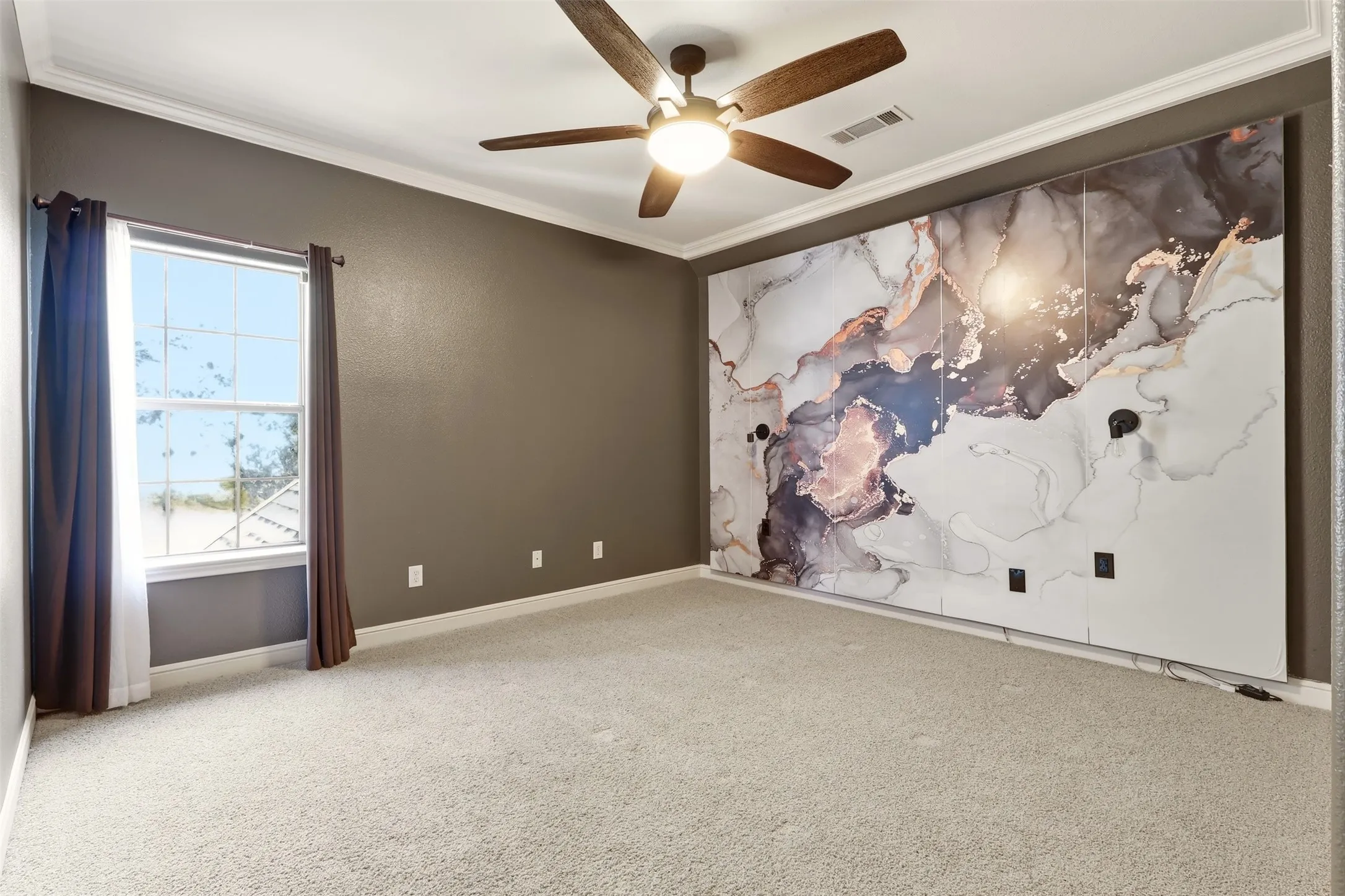 Luxe lighting, crown molding, ceiling fan with integrated light, window with white trim, and custom wall feature