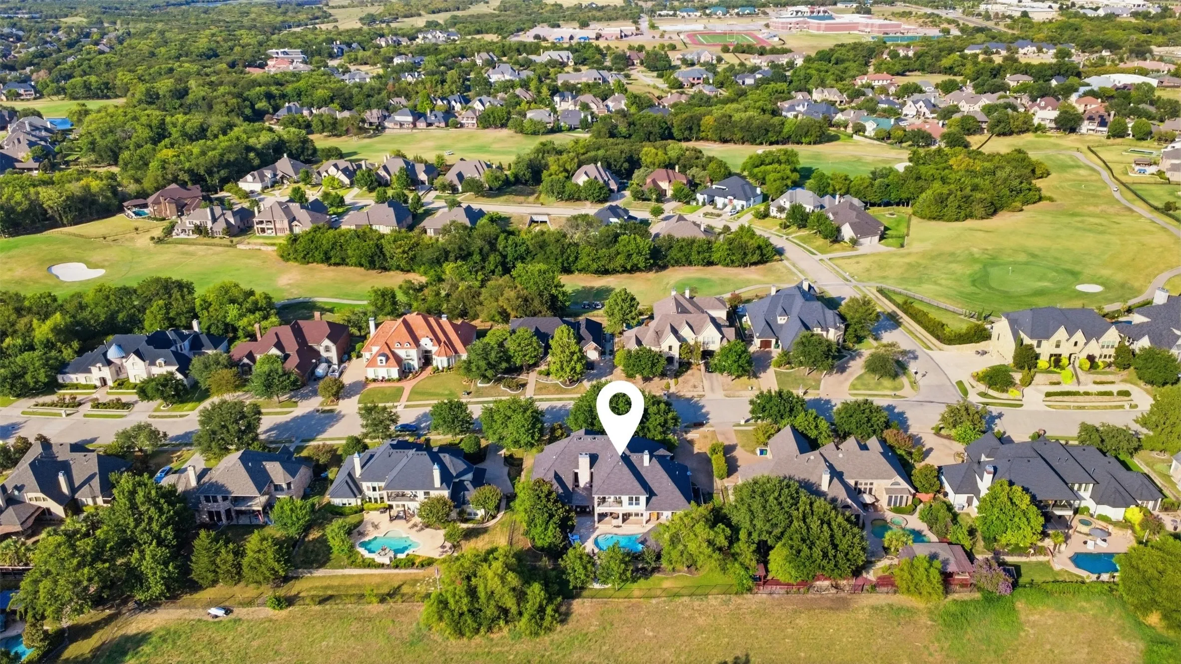 Expansive residential neighborhood with mature trees, green spaces, and multiple properties featuring private swimming pools