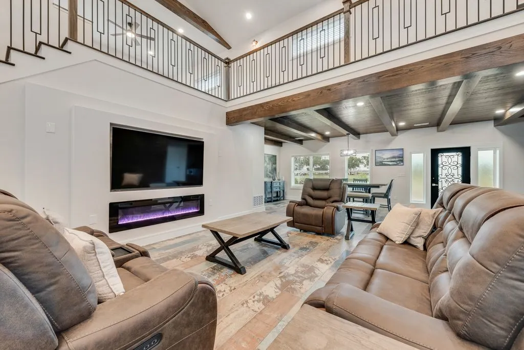 Two-story living area featuring a built-in electric fireplace and decorative wood-finish ceiling beams