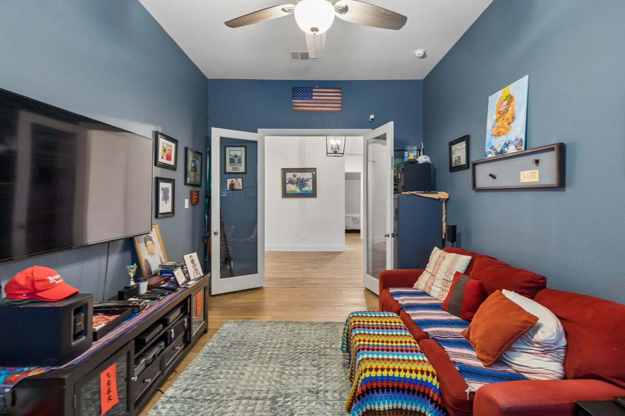 Living area featuring high ceilings, wood-finish flooring, and a ceiling fan with integrated lighting
