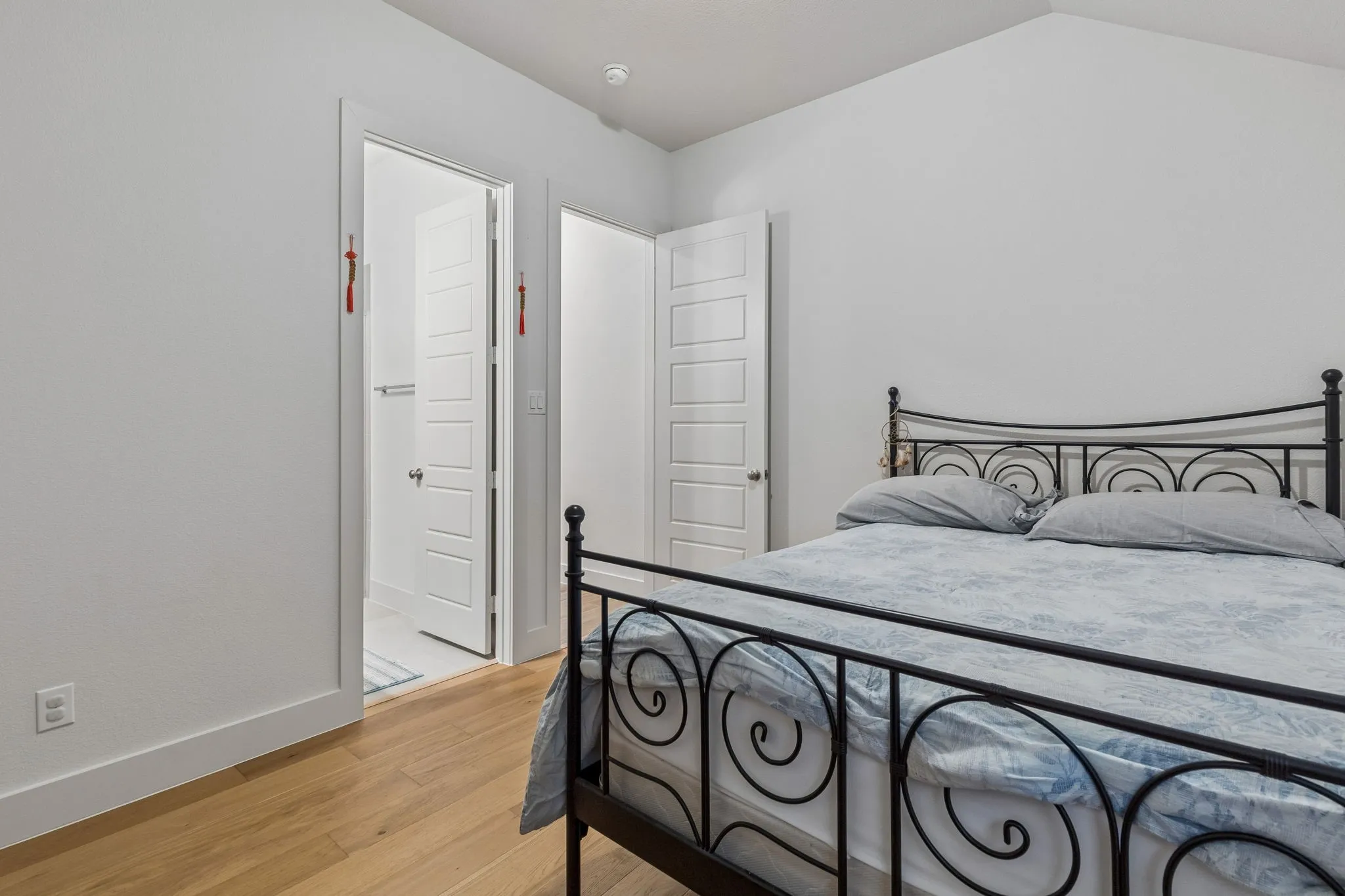 Bedroom featuring wood-finish flooring, white walls, and a vaulted ceiling