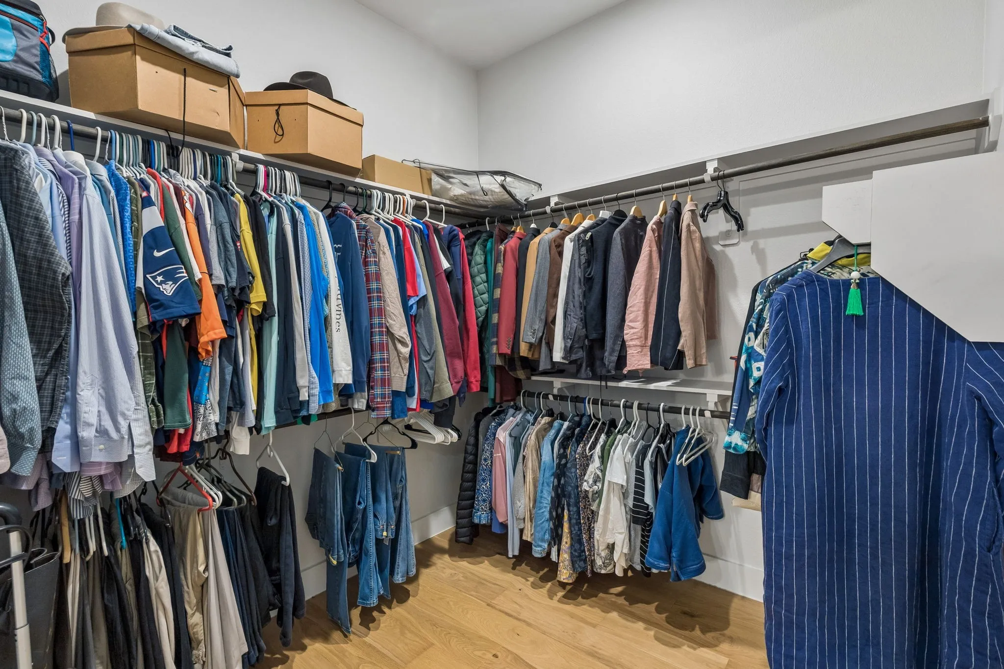 Walk-in closet featuring white walls, wood-finish flooring, and multi-level hanging storage rods