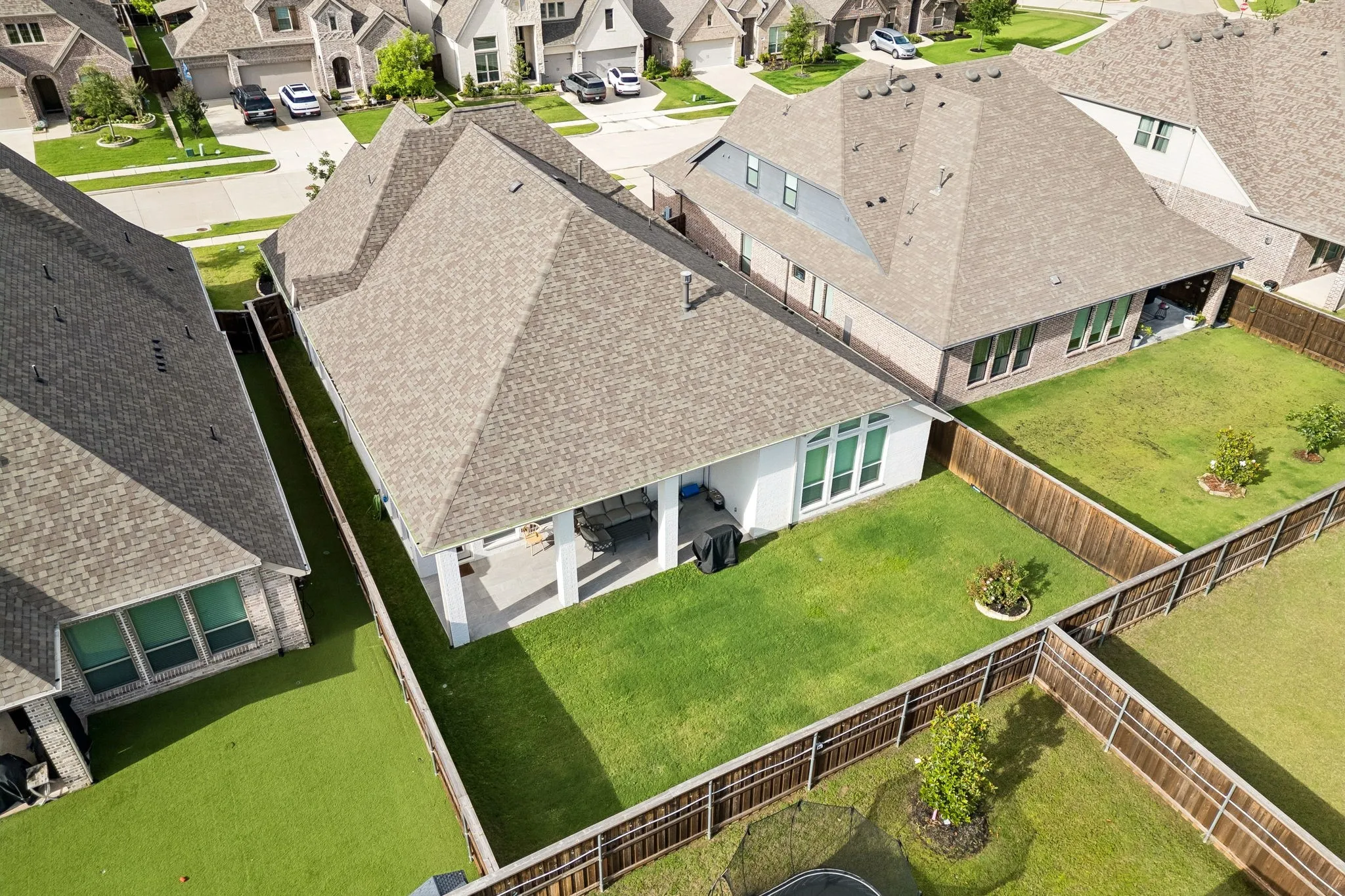 Expansive backyard featuring a covered patio, manicured lawn, and privacy fencing