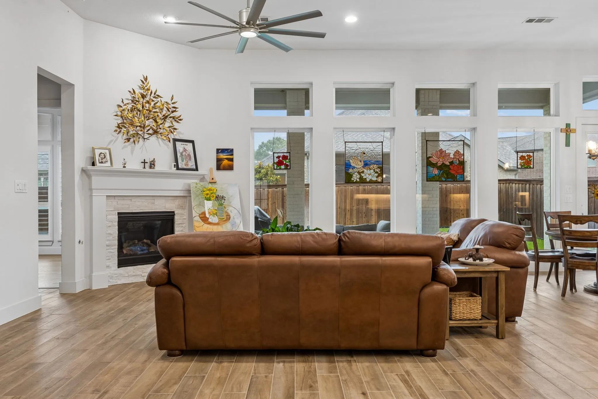Spacious living area featuring high vaulted ceilings, wood-finish flooring, and a corner fireplace with a white mantel and light-toned stone surround