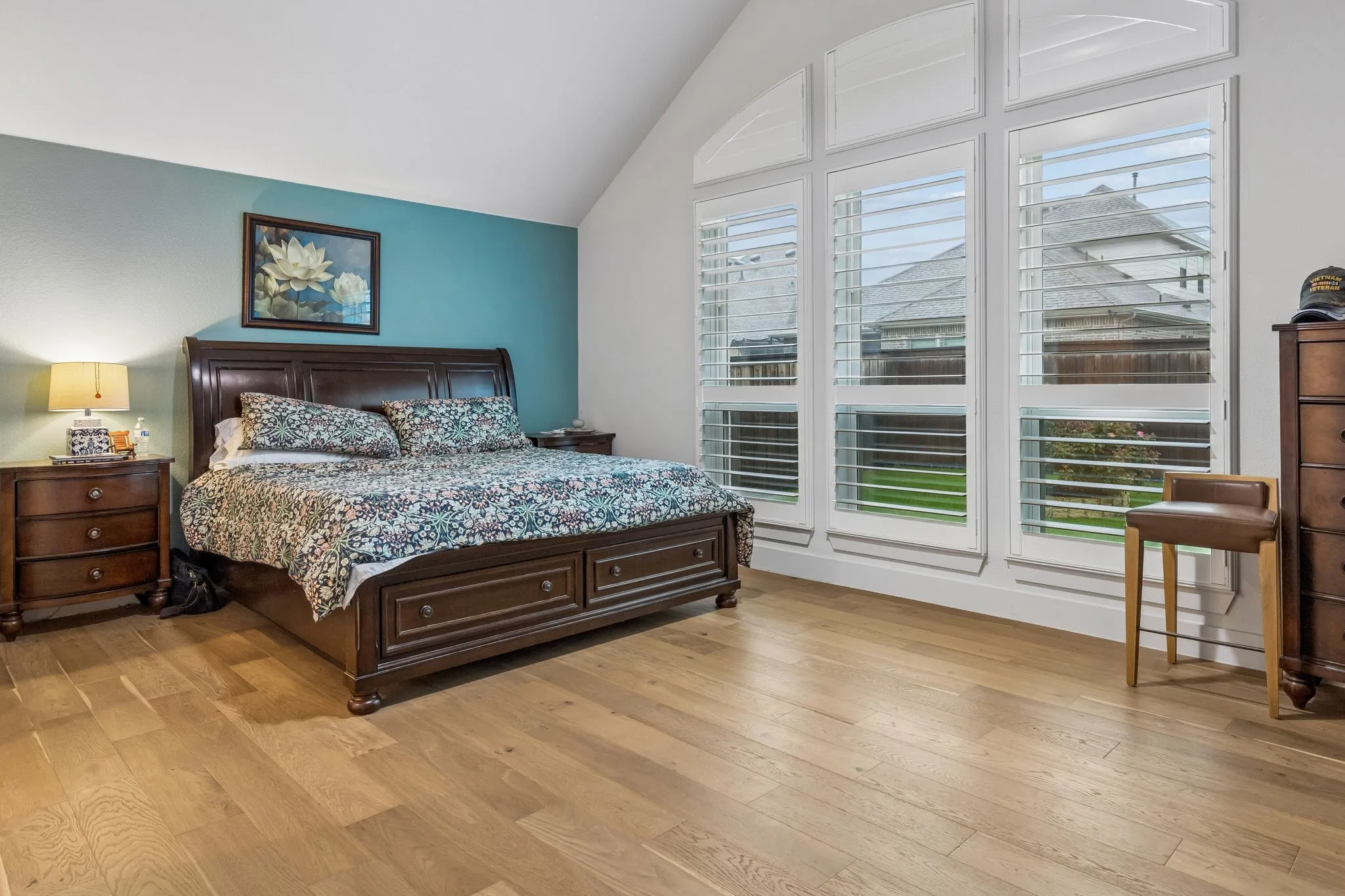 Spacious room featuring wood-finish flooring, a vaulted ceiling, and a prominent accent wall