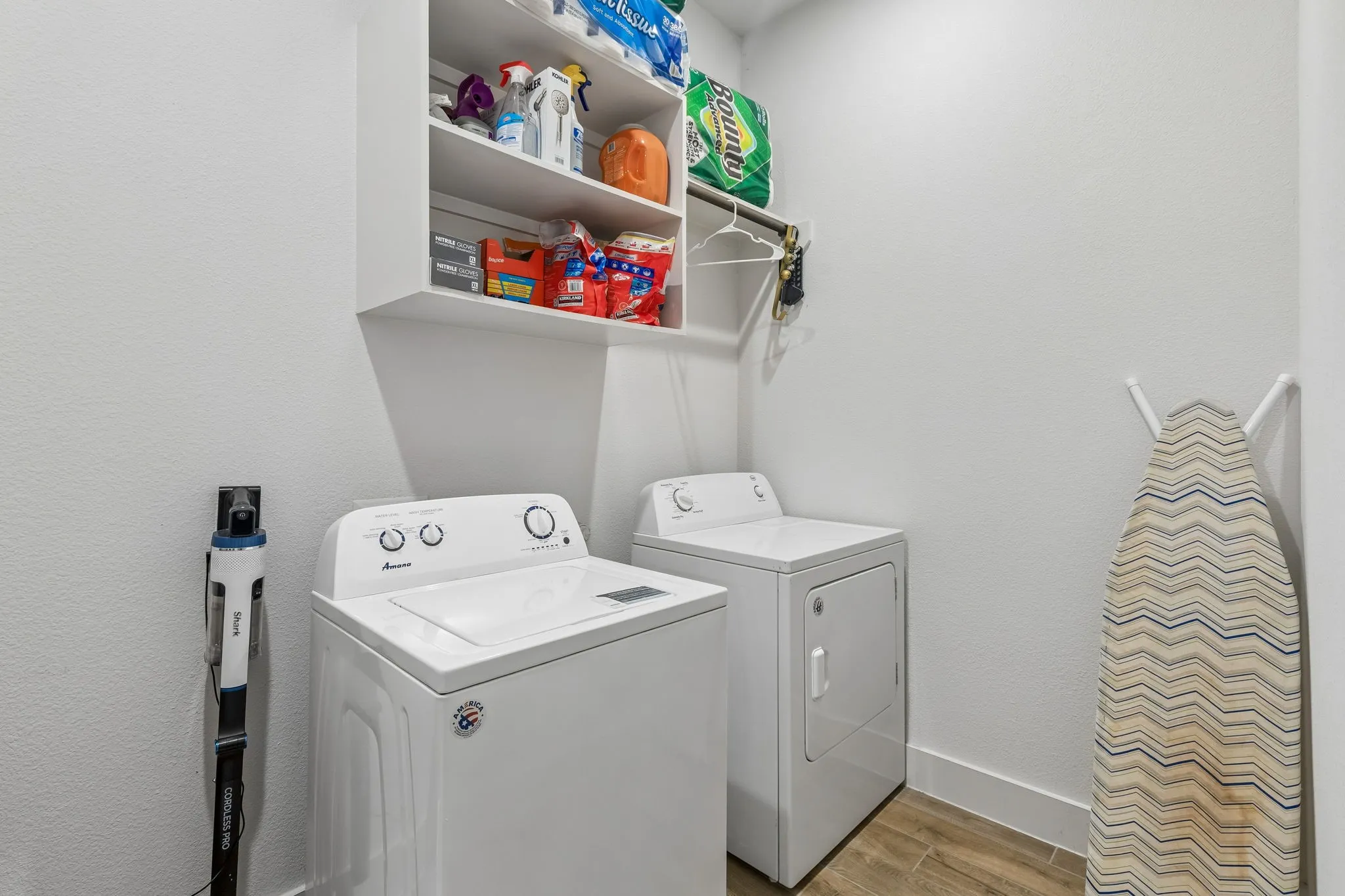 Dedicated laundry space featuring a washer and dryer, built-in shelving, a clothes rod, and wood-finish flooring
