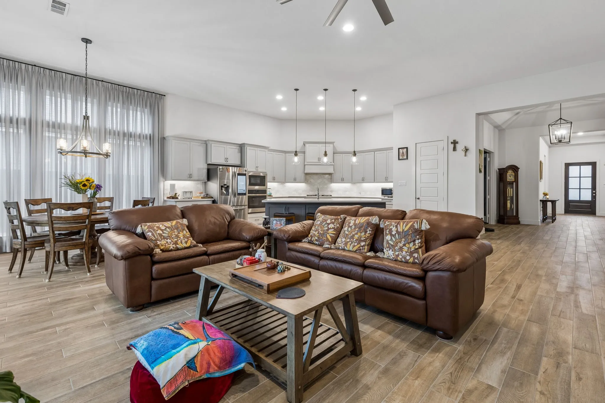 Spacious open-concept living area featuring wood-finish flooring, recessed lighting, and a contemporary ceiling fan