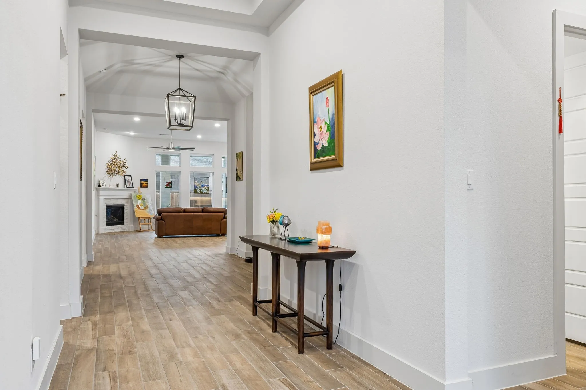 Long hallway with wood-finish flooring, vaulted ceiling, and recessed lighting