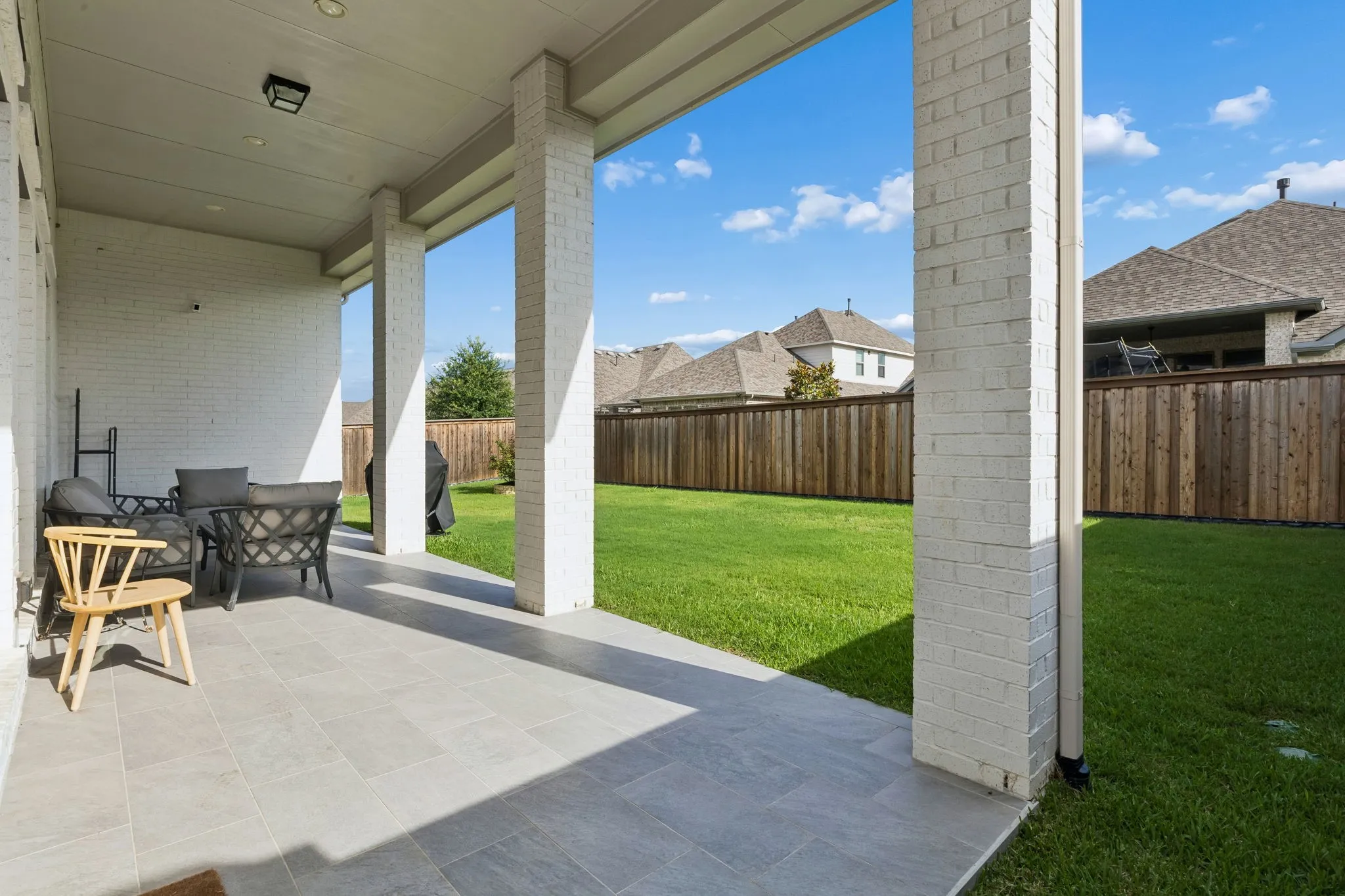 Covered patio with large format tile flooring and white painted brick columns