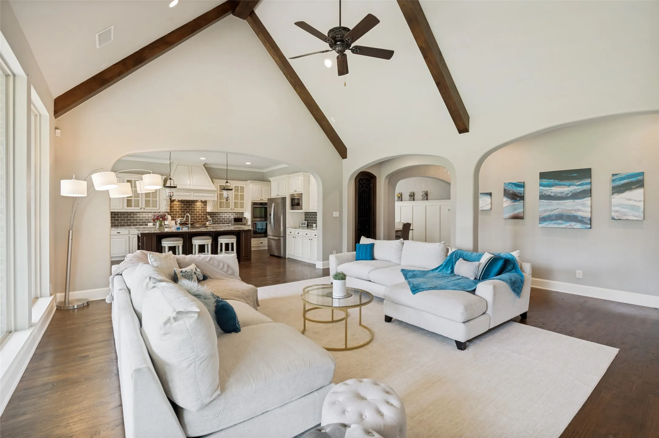 The oversized living room offers plenty of room for entertaining or relaxing, all while remaining connected to the beautifully appointed chef’s kitchen. Arched openings, rich hardwood floors, and abundant natural light enhance the inviting atmosphere, making this home ideal for hosting holidays, celebrations, or everyday moments together.