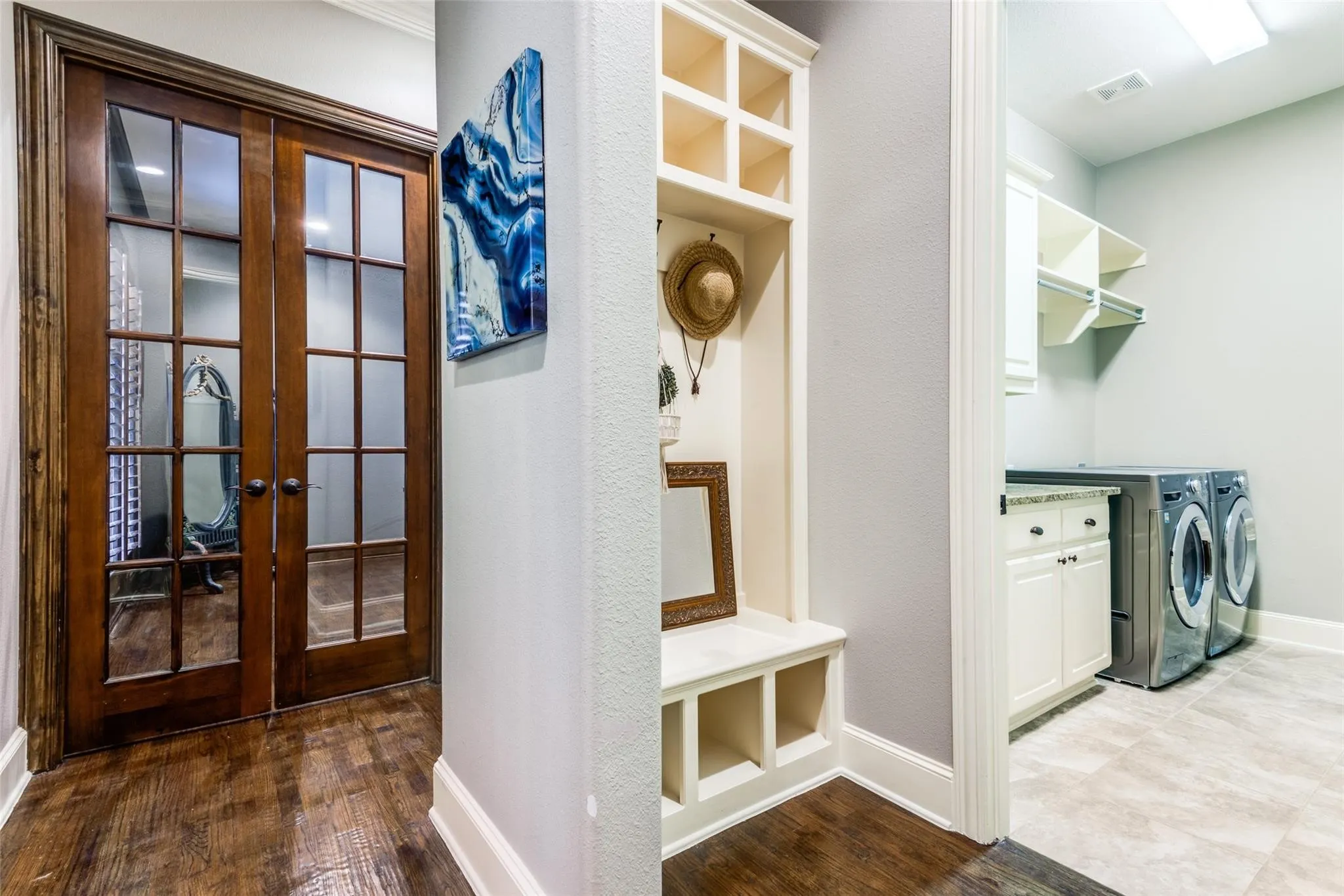 Thoughtfully designed for everyday convenience, this functional mudroom and laundry area offers the perfect blend of organization and style. The built-in mud bench with open cubbies and upper storage provides a dedicated space for everyday essentials, helping keep the home neat and organized. The oversized laundry room features abundant cabinetry, generous countertop workspace for folding and sorting, and ample hanging and storage space. Large enough to handle the demands of a busy household, this well-appointed utility room combines practicality with luxury, making everyday tasks more efficient and enjoyable.