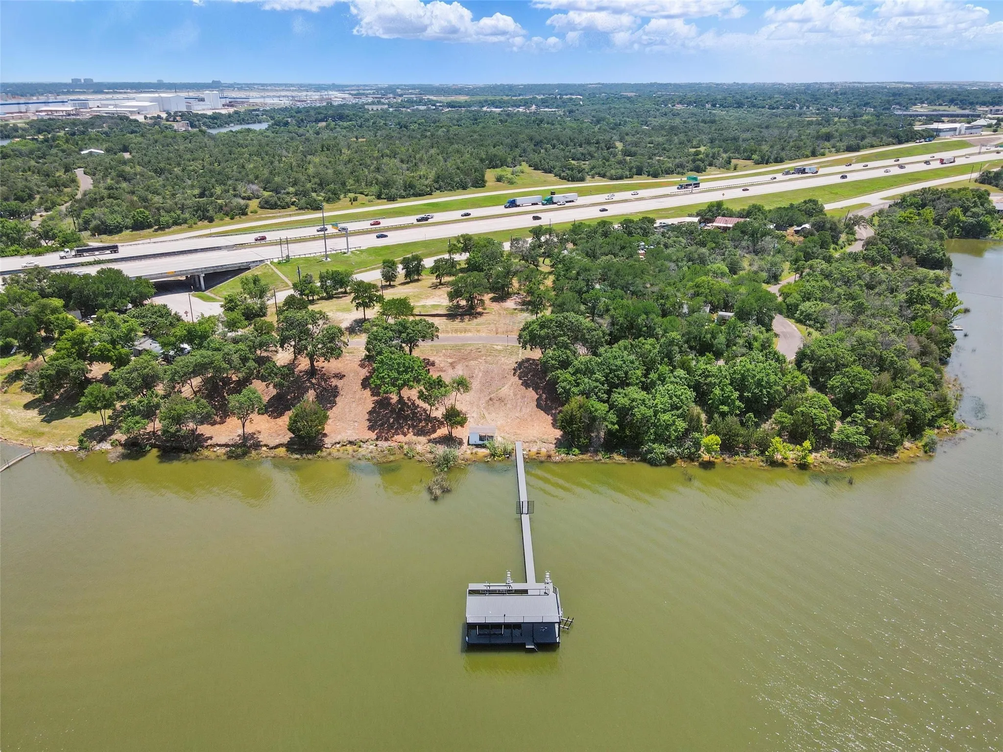 Aerial view of a highway, a large body of water, and a tree filled landscape
