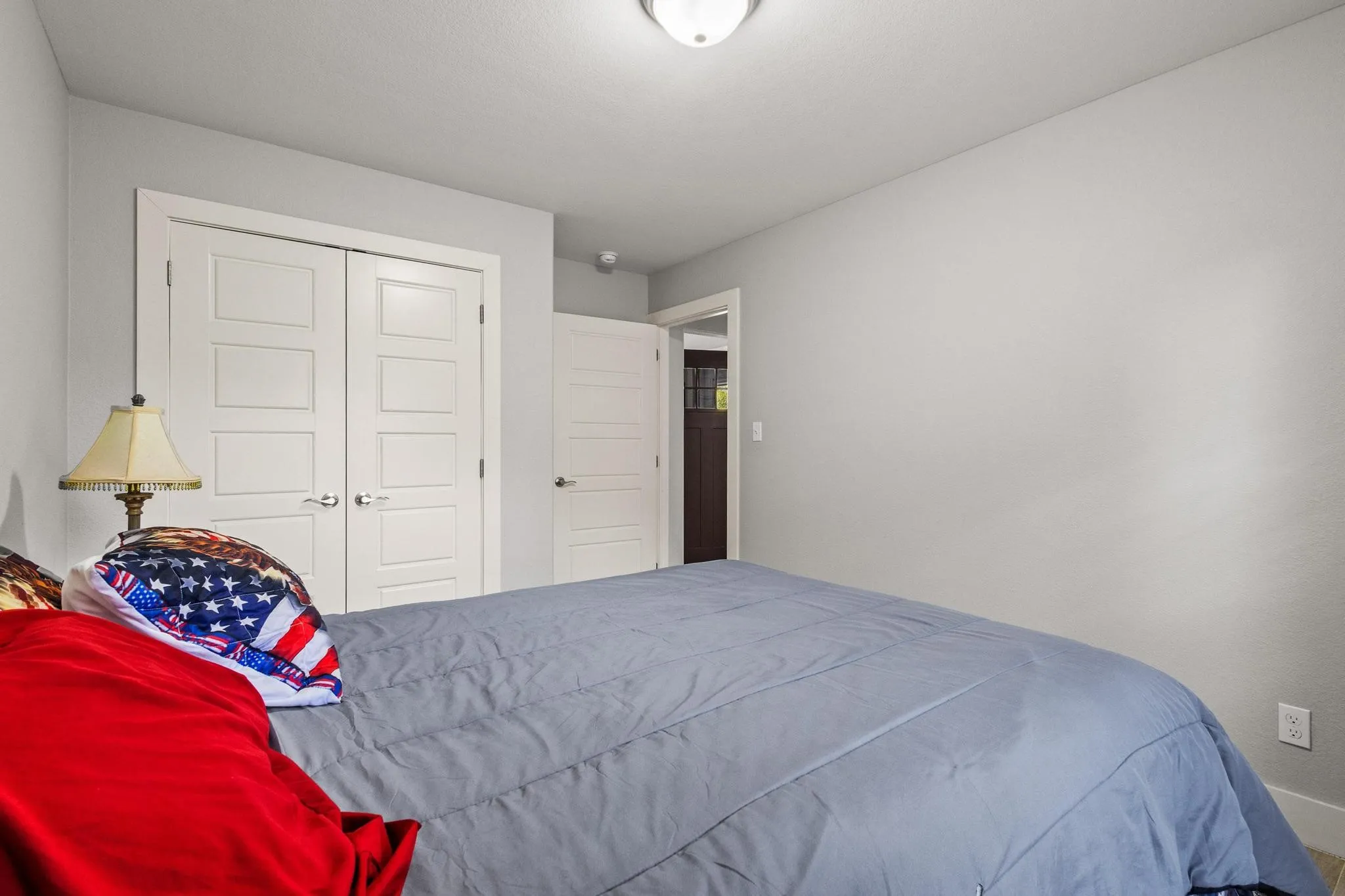 Recessed panel closet doors, light gray wall finishes, and a white ceiling with a flush-mount light fixture