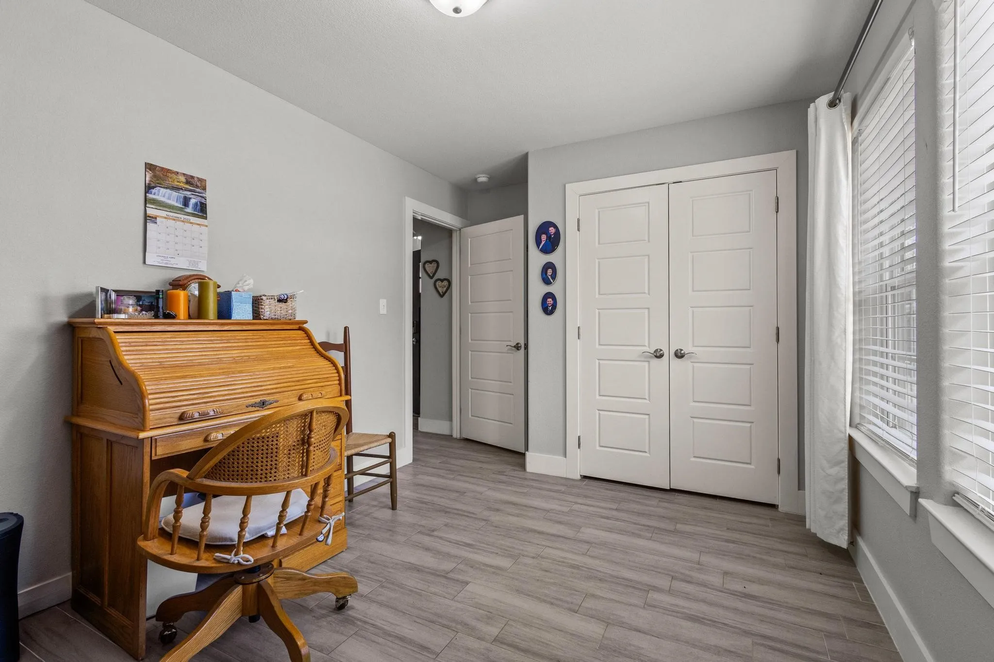 Room featuring light gray walls, wood-finish plank flooring, and white trim