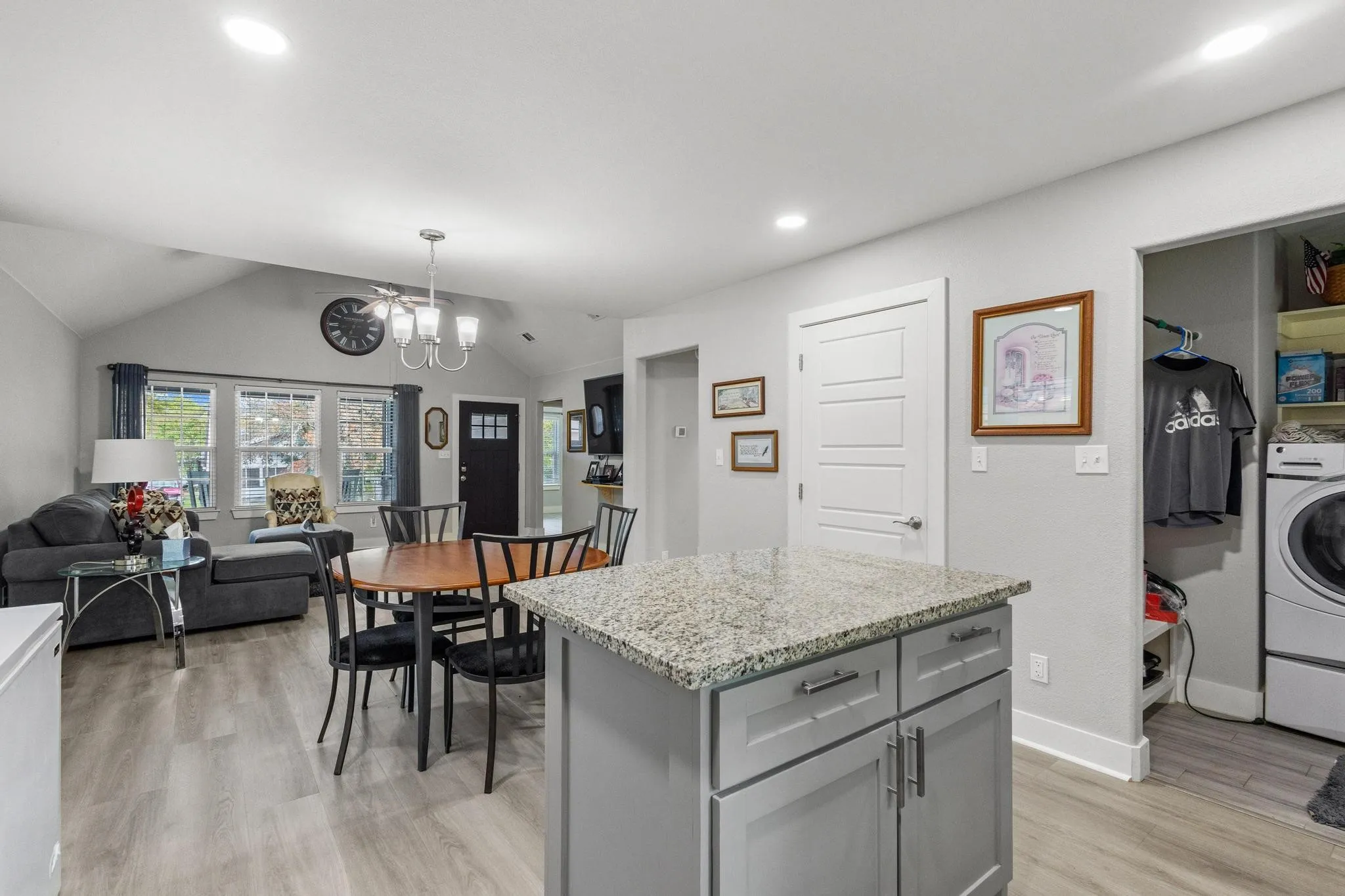 Kitchen island with granite countertop, gray cabinetry, and stainless steel hardware