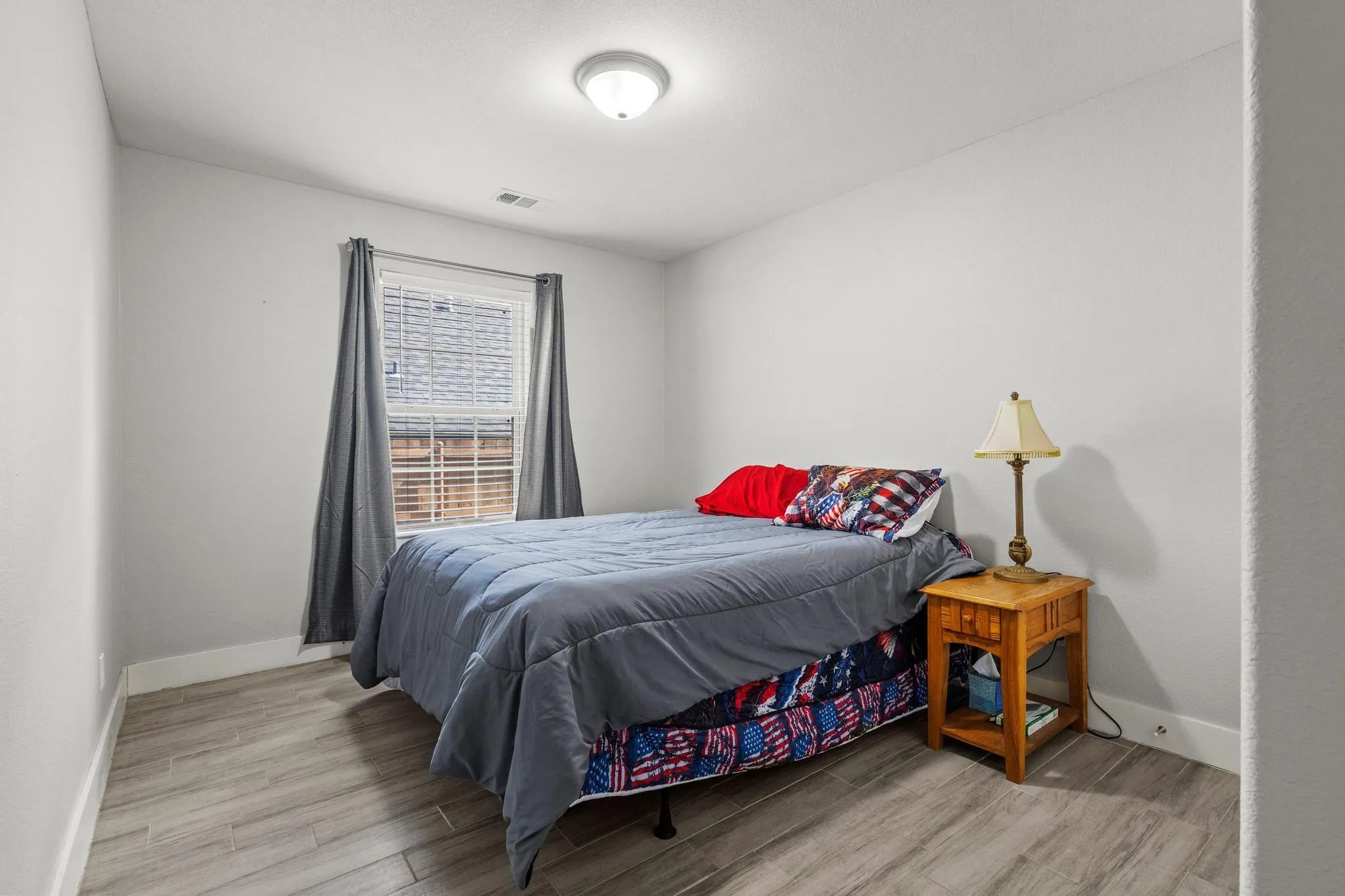 Room featuring light gray walls, wood-finish flooring, and a ceiling-mounted light fixture