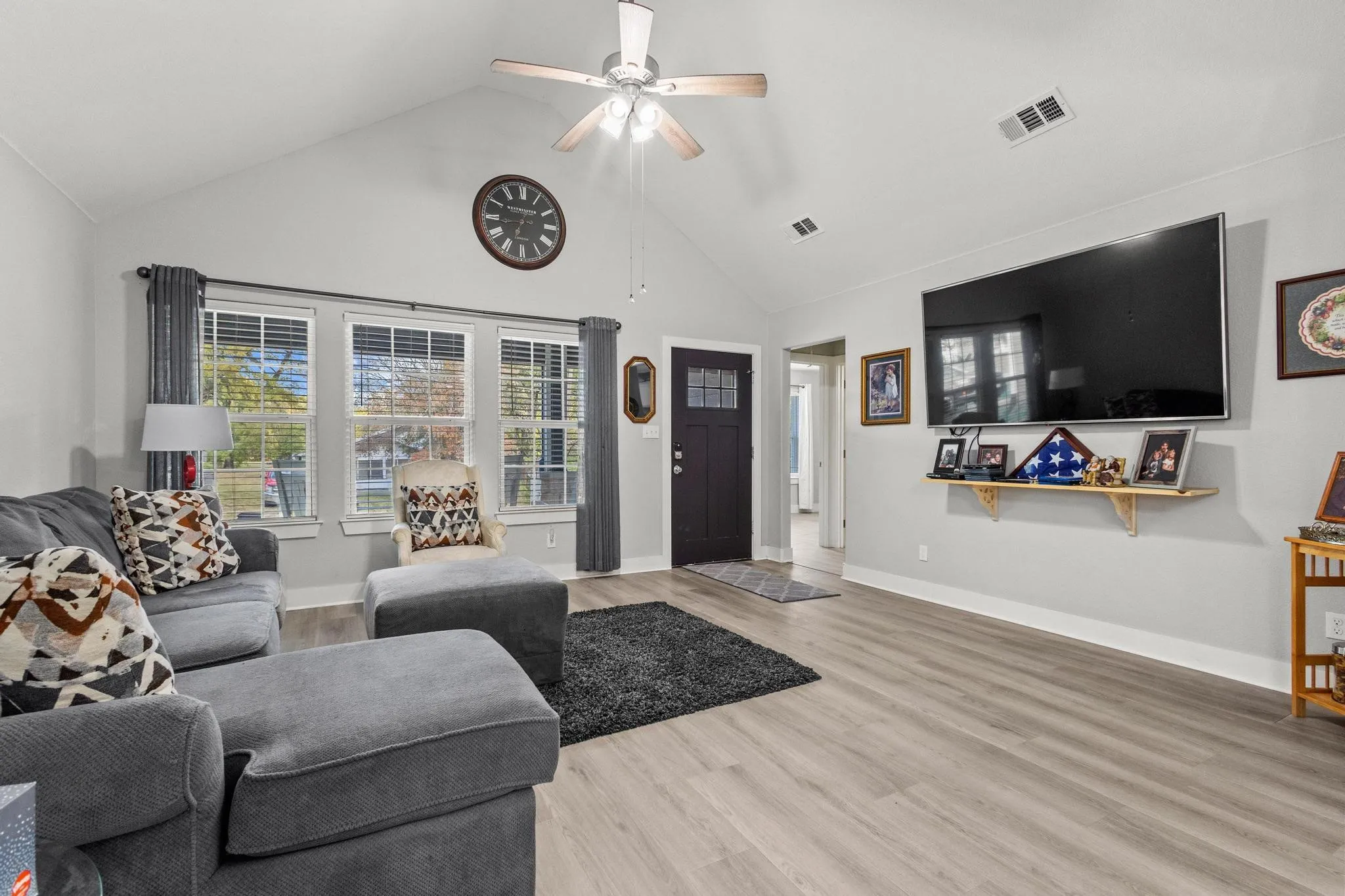 Vaulted ceiling living area featuring light wood-finish flooring and light gray wall paint