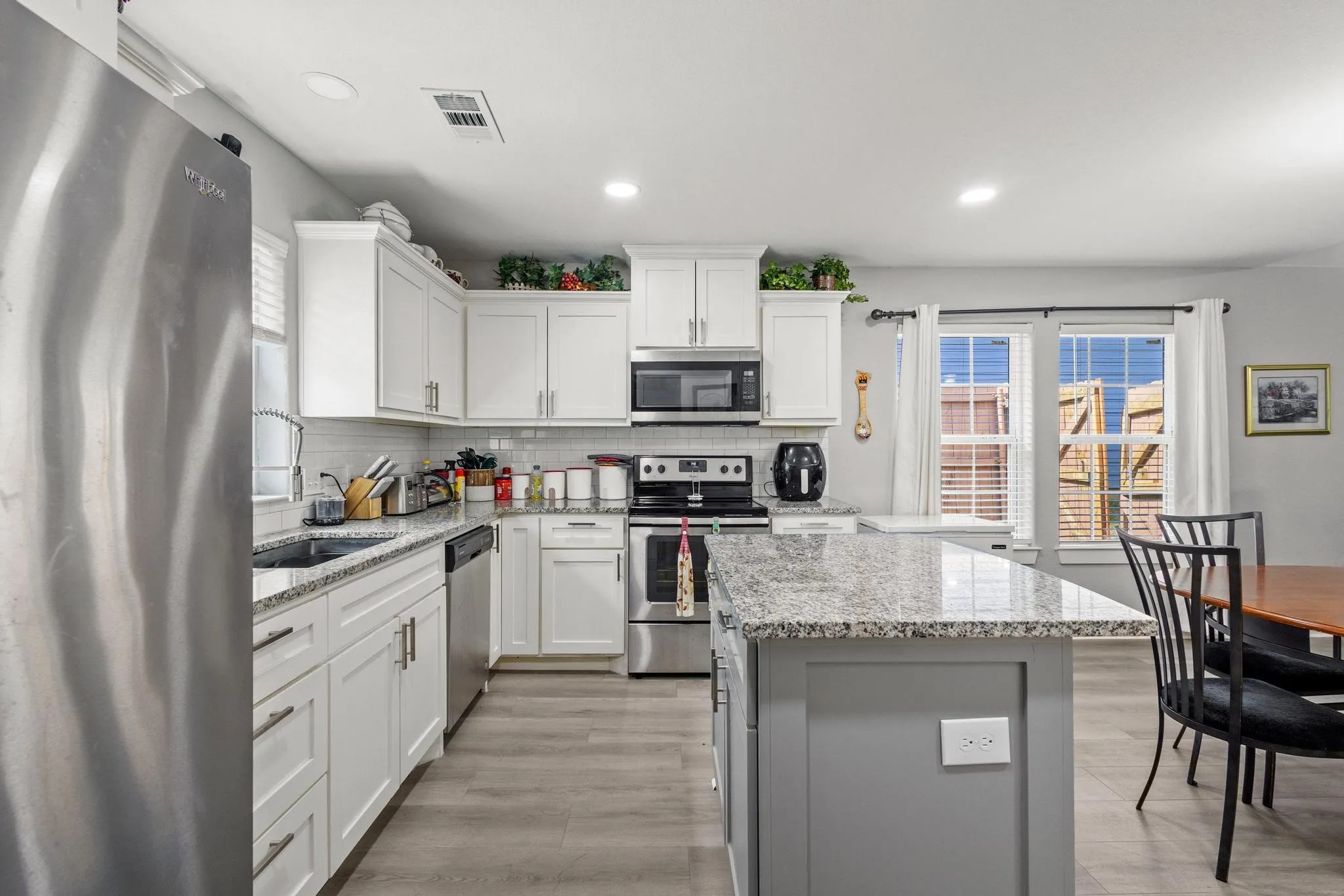 Kitchen featuring white shaker cabinetry, stainless steel appliances, speckled stone countertops, a subway tile backsplash, and recessed lighting