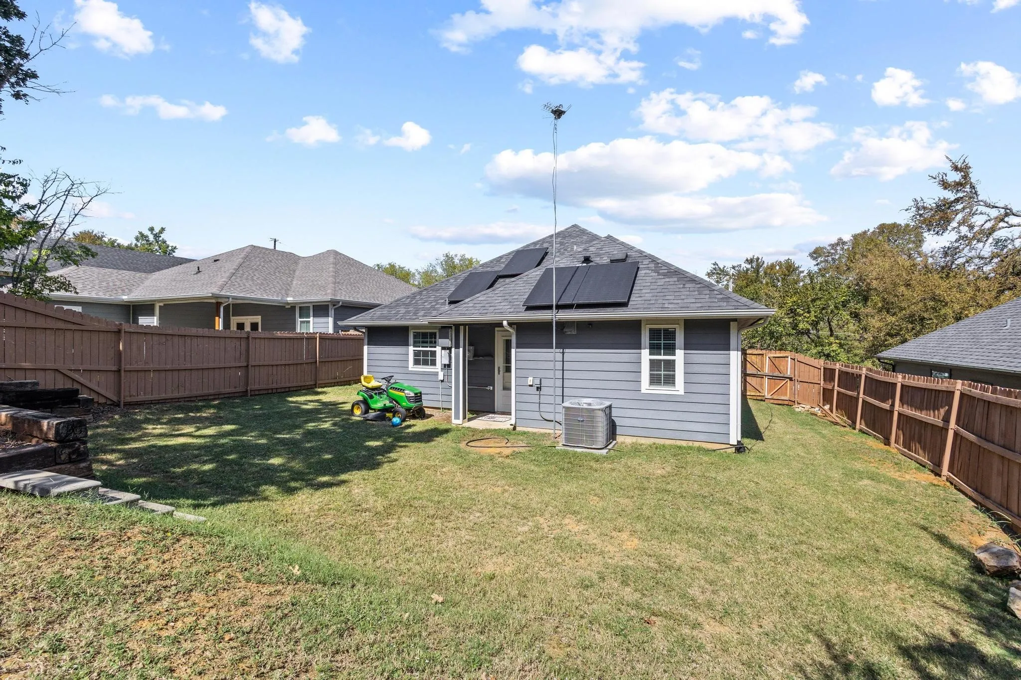 Fenced backyard with a sloped lawn and mature trees