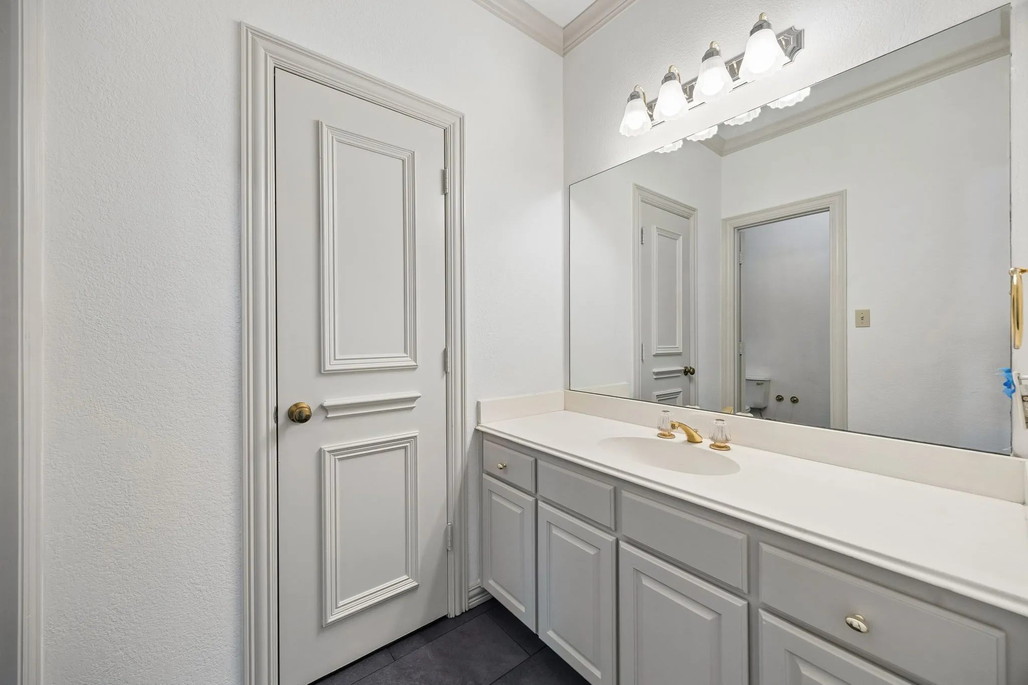 Bathroom vanity featuring an integrated sink, gold-finish faucet, and substantial mirror