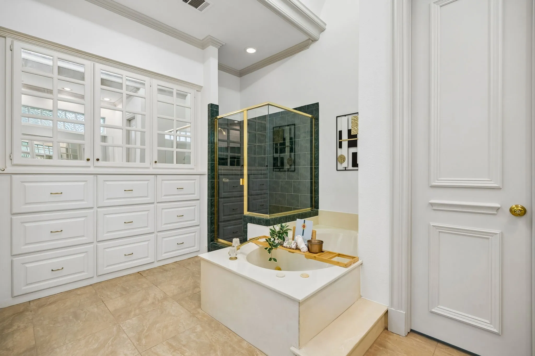 Built-in soaking tub with steps, complemented by a glass-enclosed shower featuring dark green tile