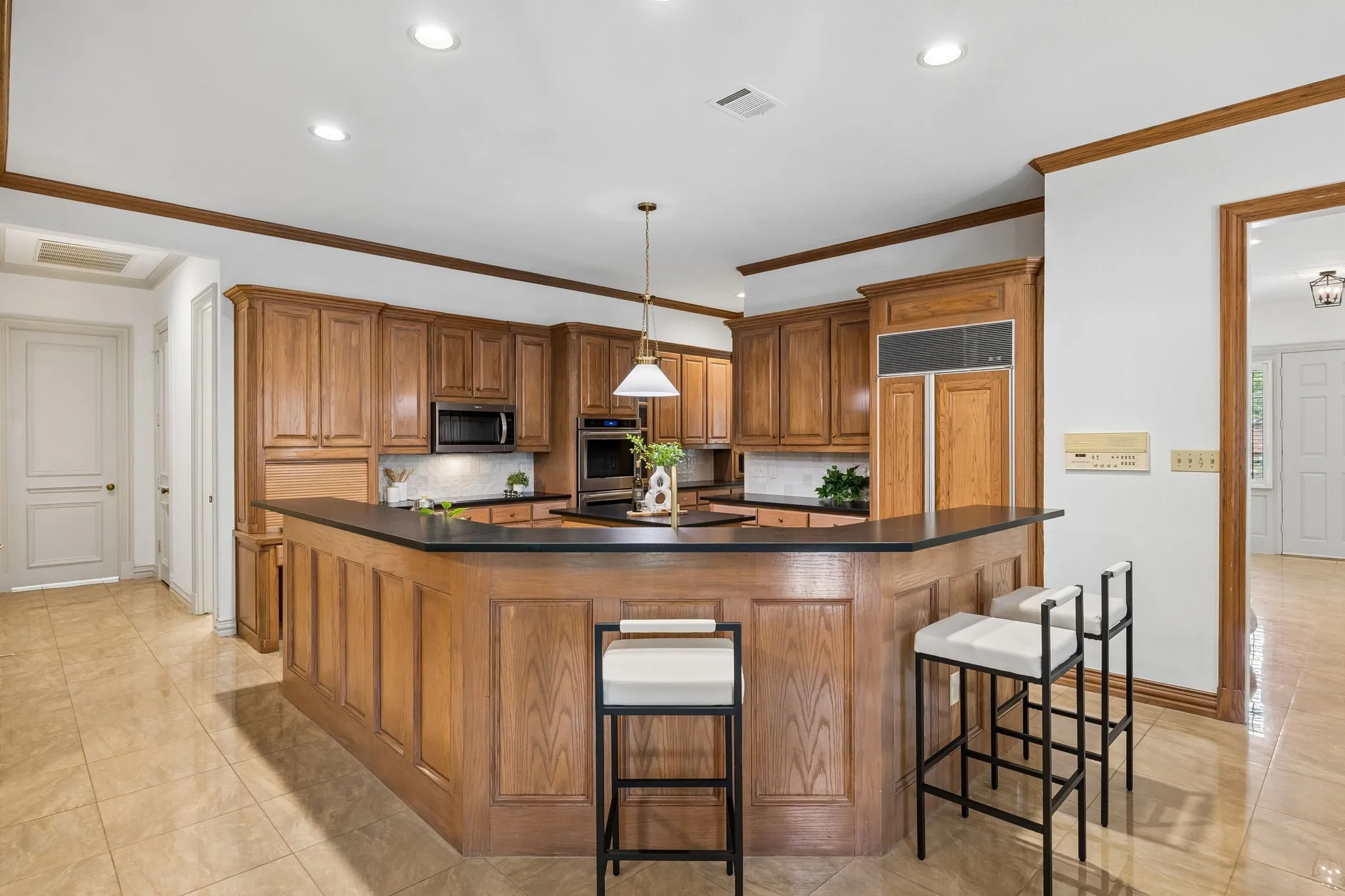 Kitchen featuring extensive wood cabinetry, a dark countertop, integrated appliances, and recessed lighting