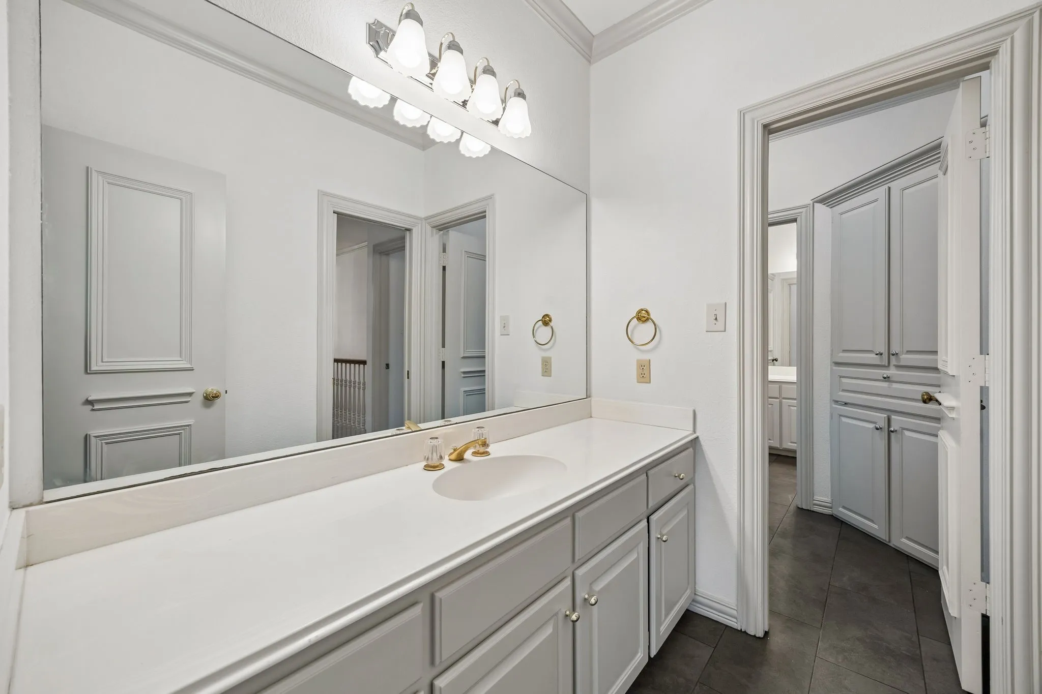 Spacious vanity featuring a white countertop with an integrated sink and gold-tone faucet