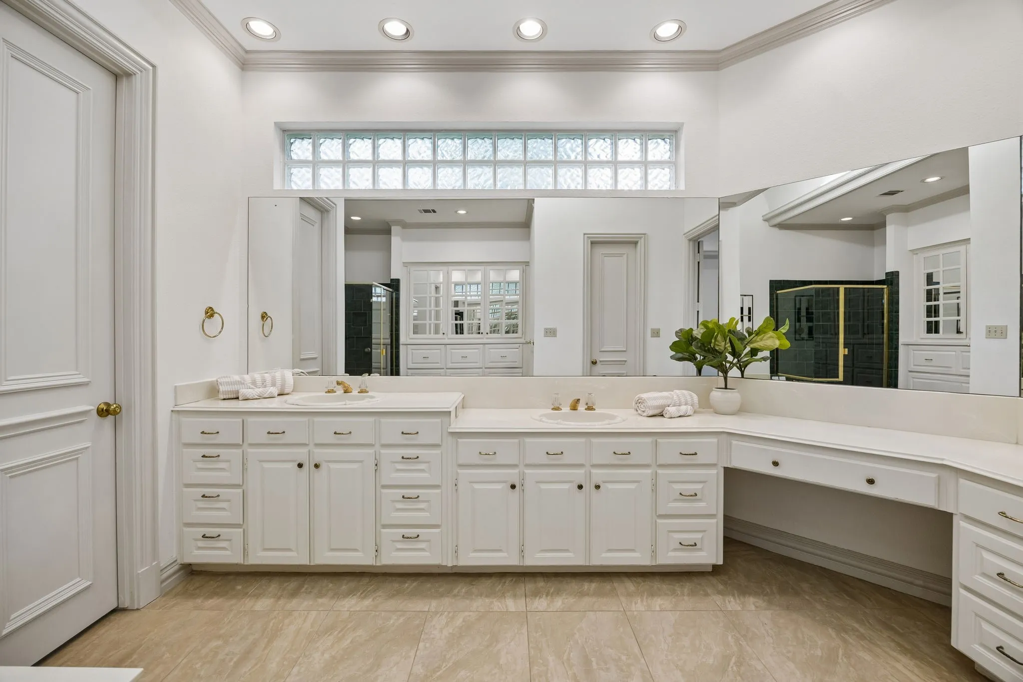 Spacious vanity area featuring dual integrated sinks, extensive countertop space, white cabinetry with multiple drawers, and a large mirror